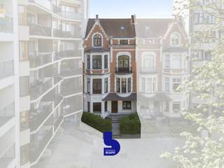 Op een uitzonderlijke ligging, tegen de Koninklijke Stallingen en pal aan het charmante Prinses Stefanieplein bevindt zich deze prachtige eclectische herenwoning, die deel uitmaakt van een zeldzaam samenspel van twee burgerhuizen uit het begin van de 20ste eeuw. Op slechts enkele stappen van het strand en de Zeedijk geniet u hier van rust, groen en een uiterst centrale ligging.<br /><br />Als één van de weinige overgebleven herenwoningen op dit plein ademt deze eigendom authenticiteit, klasse en geschiedenis. De charmante voortuin met sierlijke haag vormt meteen een stijlvolle eerste indruk.<br /><br />Het gelijkvloers beschikt over een volwaardig afzonderlijk woongedeelte met een gezellige leefruimte, geïnstalleerde keuken, slaapkamer en badkamer. Dankzij deze indeling leent de woning zich perfect voor een combinatie van wonen en praktijkruimte, een kangoeroewoning of een aparte gastenverdieping. De leefruimte wordt gekenmerkt door een prachtig origineel parket dat zich in uitstekende staat bevindt.<br />De woning is bovendien volledig onderkelderd, wat zorgt voor extra opslag- en gebruiksmogelijkheden.<br /><br />Op de eerste verdieping bevindt zich de indrukwekkende hoofdleefruimte met authentieke parketvloeren en elegante erkers die uitkijken op het groene Prinses Stefanieplein. Aansluitend vinden we een volledig geïnstalleerde keuken met toegang tot een zuid georiënteerd terras.<br /><br />De bovenliggende verdiepingen bieden meerdere ruime slaapkamers, elk voorzien van prachtige parketvloeren, sierlijsten en het typische karakter dat men in een herenwoning verwacht. Verder zijn er twee ruime, volledig ingerichte badkamers, waaronder een badkamer met ligbad en douche.<br /><br />De bovenste verdieping en zolder bieden bijkomende mogelijkheden. <br /><br />Technisch bevindt deze woning zich eveneens in uitstekende staat:<br />✔ Conforme elektrische installatie<br />✔ Verwarming op aardgas<br />✔ Energiezuinig EPC-label C voor een herenwoning<br />✔ Daken reeds vernieuwd<br />✔ Gevel in optimale staat<br /><br />Indien gewenst kan een naast gelegen garagebox mee aangekocht worden.<br /><br />Alle grote werken zijn reeds uitgevoerd, waardoor de toekomstige eigenaar zich volledig kan focussen op verdere verfijning en persoonlijke invulling.<br />Een uitzonderlijke eigendom voor wie op zoek is naar ruimte, authenticiteit en een unieke ligging aan zee.