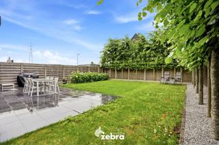 Bezoekmoment op zaterdag 04/07 van 10u tot 12u. (enkel op afspraak).<br /><br />De woning (BJ 2015) combineert hedendaags wooncomfort met uitstekende energieprestaties dankzij vloerverwarming, een warmtepomp en zonnepanelen, goed voor een uitzonderlijk energiezuinig EPC-label A+. Verder beschikt de woning over diverse extra voorzieningen, waaronder domotica, een ventilatiesysteem D, een waterverzachter en een regenwaterput van 15.000 liter.<br /><br />Via de inkomhal met gastentoilet betreedt u de woning. De lichtrijke leefruimte met volledig uitgeruste open keuken vormt het hart van de woning.<br />De keuken werd afgewerkt met kwalitatieve materialen en is uitgerust met moderne toestellen, waaronder een inductiekookplaat met geïntegreerde afzuiging, twee combi-ovens, .. Aansluitend bevindt zich een praktische keukenberging.<br /><br />Op de eerste verdieping zijn er vier volwaardige slaapkamers (plat dak), allemaal voorzien van internet- en tv-aansluitingen. De ruime badkamer beschikt over een dubbele wastafel, ligbad en douche. Daarnaast is er een afzonderlijk toilet aanwezig.<br /><br />De zonnige, zuidwestgerichte tuin biedt een aangename buitenruimte en beschikt over een praktische uitweg naar de bijhorende garagebox, inbegrepen in de prijs. Verder zijn er een zonneluifel en een tuinhuis aanwezig. Via het poortje aan de rechterzijde van de woning is de tuin bovendien gemakkelijk bereikbaar.<br /><br /><strong>Ook wild geworden van deze thuis?<br />Twijfel niet langer en leg vandaag nog uw bezoek vast!</strong>