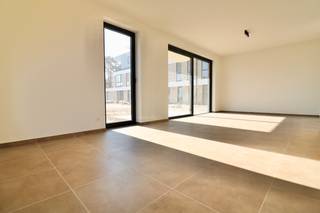 Welkom bij het Edward Poppe Woonpark, een uniek nieuwbouwproject in Sint-Laureins. Dit woonproject, gelegen op de terreinen van het voormalige Edward Poppe Instituut aan de Rommelsweg, biedt een harmonieuze combinatie van moderne architectuur en historische charme. Het project is ontworpen met oog voor detail en duurzaamheid.
Het Edward Poppe Instituut, gebouwd in 1962, diende jarenlang als een vertrouwde brug tussen de basisschool in Sint-Laureins en de grotere secundaire scholen in Eeklo, Maldegem en Gent. Het gebouw, bekend om zijn modernistische stijl en familiaire sfeer, is een herkenningspunt in de regio en biedt een prachtige basis voor dit nieuwe woonproject.
Het Edward Poppe Woonpark streeft naar een energie-neutraal karakter. Geen gebruik van fossiele brandstoffen, maar wel van warmtepompen en zonnepanelen, duurzame materialen en hergebruik en renovatie van bestaande structuren. De circulatie van auto's is slim ontworpen aan de buitengrenzen van het perceel, waardoor de kern van het project een groene oase blijft.
De indeling is als volgt: een grote inkomhal met gastentoilet, een lichtrijke leefruimte met een prachtig uitzicht op de privatieve tuin met terras en de gemeenschappelijke tuin, een open keuken voorzien van alle hedendaagse comfort met voldoende opbergruimte, 2 slaapkamers, een badkamer, een grote berging/wasplaats, een privatieve fietsenberging/berging en een privatieve autostaanplaats.
Alle leefruimtes kijken uit op een centraal groen park, dat dienst doet als ontmoetingsplaats voor jong en oud. Het park, met zijn glooiende reliëf, draagt bij aan een natuurlijke speelomgeving en fungeert tevens als wadi.
Het appartement is volledig geschilderd en instap klaar.
Wonen in Sint-Laureins biedt tal van voordelen. De gemeente staat bekend om haar uitstekende leefkwaliteit, met een sterke focus op natuur, rust en veiligheid. Daarnaast zijn er uitgebreide voorzieningen voor sport, cultuur en recreatie. De nabijheid van stedelijke centra zoals Eeklo, Maldegem en Gent zorgt ervoor dat stedelijke voorzieningen altijd binnen handbereik zijn.
Ontdek de perfecte balans tussen historisch erfgoed en modern wooncomfort in het Edward Poppe Woonpark. Wenst u een bezoek aan het gelijkvloers appartement? Maak uw afspraak via www.vastgoedunicum.be of mail naar verhuur@vastgoedunicum.be.