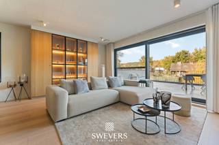 Interesse? Meer informatie op www.SWEVERS.be. - Dit exclusieve duplex villa-appartement combineert de luxe van een villa met het comfort van een appartement en bevindt zich in een stijlvolle, kleinschalige residentie met slechts vier wooneenheden. De ruime, lichtrijke leefruimte met parketvloer, maatwerkkasten en gashaard vormt het elegante hart van de woning en sluit naadloos aan op de moderne, volledig uitgeruste keuken. Via grote schuiframen kom je op het riante terras van 35,4 m², waar je geniet van de avondzon en een groen uitzicht – een perfecte verlenging van de leefruimte.<br /><br />Op de bovenverdieping bevinden zich twee royale slaapkamers, waaronder een master van 22 m² met hotelallure, en een tweede kamer die ideaal is als gastenkamer, bureau of dressing. De luxueuze badkamer met inloop-regendouche en ligbad straalt pure verfijning uit. Extra troeven zijn de zolder van 100 m² voor extra opslag, twee autostaanplaatsen in de carport en een praktische berging van 7,5 m². Comfort en veiligheid staan centraal dankzij alarm, videofoon, beveiligde deur, rookdetectoren, airco en een energiezuinig E-peil van E44.<br /><br />De ligging is optimaal: scholen, openbaar vervoer, winkels en restaurants liggen op wandelafstand, terwijl je in 2 minuten op de snelweg staat en in 15 minuten in Hasselt bent. Natuurgebieden zoals De Kluis en Domein Bovy liggen vlakbij, waardoor rust en bereikbaarheid perfect in balans zijn. Dit instapklare appartement uit 2019 biedt een uitzonderlijke woonbeleving voor wie houdt van ruimte, luxe en verfijning. Bel ons vandaag nog voor een persoonlijke rondleiding. Wij van Swevers Real Estate helpen je maar al te graag verder. tel. 011 255 155. Bron bewoonbare oppervlakte: EPC – verslag.