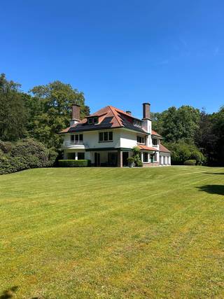 <span>Kasteeldreef 38 - 2950 Kapellen Deze karaktervilla werd gebouwd omstreeks 1937 en is omgeven door een prachtige parktuin van ca 10.812 m² met prachtige aanplantingen en oude monumentale bomen. Het is een klassieke Franse stijl villa die steeds tip top werd onderhouden en verschillende mogelijkheden biedt. De woning straalt enorm veel grandeur en charme uit en werd in ... grondig gerenoveerd. De villa is als volgt ingedeeld: Royale inkomhal op tegelvloer met gastentoilet met handenwasser en vestiairekast. Doorgang naar ruime leefruimte met gashaard, veel ramen en natuurlijke lichtinval. Toegang tot overdekt terras. Hiernaast bevindt zich nog een tweede leefruimte of eetkamer met zicht op tuin en terras en gashaard. Aansluitend bevindt zich nog een open ruimte die momenteel wordt gebruikt als kantoor. Verder komt u in de volledig ingerichte keuken, voorzien van alle toestellen en ingemaakte kasten + ontbijthoek. Naast de keuken is er nog een grote polyvalente ruimte, momenteel gebruikt als kantoor of vergaderruimte, weer met grote raampartijen die uitgeven op de mooie parktuin. Naast de keuken toegang tot de ruime garage die plaats biedt voor 3a4 wagens. Hiernaast bevindt zich nog een badkamer met wc, douche en lavabo die hoort bij een gastenverblijf of conciërge kamer op de eerste verdieping (met aparte ingang via de keuken). Via de trap in de inkomhal toegang tot de eerste verdieping die als volgt is ingedeeld: 1e slaapkamer met aansluitend badkamer met ligbad, douche, dubbele lavabo en wc met marmer bekleed. 2e slaapkamer op vast tapijt. 3e en 4e slaapkamer op vast tapijt. Hoofdslaapkamer op vast tapijt met aansluitend hoofd badkamer met ligbad, douche, dubbele lavabo en wc. Hiernaast bevindt zich nog een aparte kamer die dienst doet als wasplaats. Via de vaste zoldertrap toegang tot de zolderverdieping die is afgewerkt en onderverdeeld in 3 kamers en een berging. Via een zolderluik nog toegang tot de bergzolder. Via de keuken is er tevens toegang tot de ruime en volwaardige kelderverdieping onderverdeeld in verschillende ruimtes: wijnkelder, technische ruimte, bergruimtes,... De ruime oprit en parking bieden plaats voor een achttal wagens. Hier is tevens een bijgebouw opgetrokken van ca 80m². Deze voormalige garage wordt nu gebruikt als seminarie ruimte en is voorzien van sanitair en elektriciteit. In de tuin werd nog een uniek kunstwerk ontworpen dat als polyvalente ruimte kan dienen. Een ideale ruimte om tot rust te komen volledig omgeven door de natuur en de parktuin. De woning met garages en bijgebouw zorgen voor zeer veel potentieel en verschillende mogelijkheden qua invulling: ruime gezinswoning, kantoor aan huis, kangoeroe wonen, conciërgewoning, kantoren,...</span>