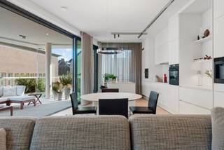 VERKOOP ONDER REGISTRATIERECHTEN. Gelegen in de Paardsdemerstraat 16 te Hasselt, bevindt zich dit uitzonderlijk ruim en energiezuinig appartement. Gelegen pal aan het Z33 en het historische Begijnhof Hasselt, woont u hier in het culturele en groene hart van de stad, met alle voorzieningen op wandelafstand. <br /><br />Een oase van licht, ruimte en comfort<br /><br />Dit uiterst energiezuinig appartement bevindt zich op de eerste verdieping en biedt volledige privacy zonder inkijk. Met een bewoonbare oppervlakte van maar liefst 150 m²(bron EPC) en plafonds van +- 3 meter hoog geniet u hier van een uitzonderlijk ruimtelijk gevoel.<br /><br />De absolute blikvanger is de indrukwekkende wintertuin van +-43 m²: een zonnig terras met verschuifbare glaspanelen, geïntegreerde plantenbakken met automatische bewatering en een naadloze overgang tussen binnen en buiten. Een unieke leefruimte die elk seizoen tot zijn recht komt.<br /><br />Dit appartement is verder tot in de puntjes afgewerkt met kwalitatieve en duurzame materialen en moderne technieken;<br />- Vloerverwarming in het volledige appartement<br />- Airconditioning in leefruimte/keuken en beide slaapkamers<br />- 5 private zonnepanelen (2010 Wp)<br />- Designverlichting, eenvoudig bedienbaar via app<br /><br />De moderne, volledig uitgeruste keuken biedt alle comfort: koelkast en diepvriezer, combi-oven, heteluchtoven, koffiehoek/machine, brede inductiekookplaat en vaatwasser.<br /><br />Indeling;<br />Ruime inkomhal met gastentoilet<br />Lichtrijke leefruimte met open keuken<br />Praktisch ingerichte wasplaats<br />Masterbedroom met ensuite badkamer (dubbele lavabo, inloopdouche, bad en toilet)<br />Tweede slaapkamer met naastgelegen badkamer (lavabo en inloopdouche)<br />Grote zuidgerichte raampartijen met screens, vliegenramen en raamdecoratie<br /><br />Ondergronds;<br />Extra brede, aparte en goed gesitueerde ondergrondse parkeerplaats (mogelijkheid tot het bij aankopen van deze extra ruime parking)<br /><br />Ruime, aparte berging incl.<br /><br />2 gemeenschappelijke binnentuinen voor extra leefkwaliteit<br /><br />2 afgesloten fietsenbergingen:<br />één in de ondergrondse garage (bereikbaar via buitenfietsenlift)<br />één in de afgesloten buitenruimte<br /><br />Dit exclusieve en instapklare appartement combineert een topligging in het centrum van Hasselt met uitzonderlijke volumes, hoogwaardige afwerking en energiezuinige technieken.