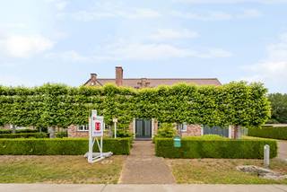 Deze ruime gezinswoning biedt zowel voor -als achteraan een groen uitzicht op bos -en landbouwgebied waardoor het hier zeer rustig vertoeven is.<br />De eigendom biedt zowel binnen als buiten zeer veel ruimte met zijn 4 slaapkamers, 2 badkamers, ruime keuken, wasplaats, inpandige garage, onderkeldering en bijgebouw van +/- 100m² achter de woning. <br />Het is eveneens mogelijk de woning volledig gelijkvloers te bewonen door de aanwezigheid van een gelijkvloerse bureau/slaapkamer en badkamer. <br /><br />We betreden deze villa via de zeer open inkomhal die onmiddellijk toegang biedt tot de gelijkvloerse bureau/slaapkamer.<br />Deze goed ingedeelde woning beschikt verder op de gelijkvloerse verdieping over een zeer ruime L-vormige woonkamer die voorzien is van vele ramen en dus veel natuurlijk licht. Deze sluit aan op de functionele keuken die verder voorzien is van wasplaats met ingemaakte kasten en douche, bergruimte, apart toilet en inpandige garage met automatische poort. <br /><br />Op de verdieping vinden we vier volwaardige slaapkamers terug. Eén hiervan kan eventueel nog opgedeeld worden in 2 aparte slaapkamers. De badkamer is eveneens zeer ruim voorzien en beschikt over dubbele lavabo, douche en ligbad. Verder is er een extra bergruimte aanwezig op deze verdieping.<br />De zolder is bereikbaar via een vlizotrap. Deze is mogelijks nog verder af te werken tot extra bewoonbare ruimte.<br /><br />Een absolute troef is de tuin die beschikt over een overdekt terras en het vrijstaande bijgebouw van maar liefst +/- 100 m² en voorzien is van een poort. Deze is ideaal als werkplaats, opslagruimte, atelier, hobbyruimte of voor wie een zelfstandige activiteit wil combineren met wonen.<br /><br />Bijzonderheden:<br />- Unieke locatie met zowel voor -als achteraan groen uitzicht<br />- Mogelijkheid extra bosgrond bij te kopen<br />- Bijgebouw van +/- 100m²<br />- Zeer ruime bewoonbare oppervlakte waardoor de woning dienst kan doen voor verschillende doeleinden<br />- Geboorde grondwaterput<br />- Alarm<br />- Rolluiken