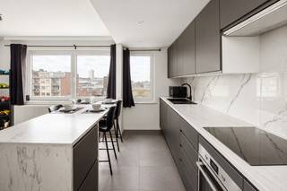 Indeling

Op de vierde verdieping van een kleinschalig gebouw met lift vinden we dit volledig gerenoveerde appartement.

Via de inkomhal heeft u toegang tot alle ruimtes. Aan de voorzijde vinden we de ruime leefruimte met aansluitend de open keuken met kookeiland. De keuken is volledig uitgerust met een inductiekookplaat, dampkap, koelkast, diepvriezer, enkele spoelbak en vaatwasser. Aansluitend bevindt zich een praktische berging met aansluitingen voor wasmachine en droogkast. Aan de achterzijde bevinden zich twee slaapkamers. De ruime hoofdslaapkamer is voorzien van airconditioning en biedt rechtstreeks toegang tot het gezellige terras.
Verder beschikt het appartement over een badkamer met modern wastafelmeubel en inloopdouche, evenals een apart toilet.

Troeven

✔ Terras aanwezig

✔ Gunstig EPC-label B

✔ Airconditioning in slaapkamer

✔ Elektriciteit conform

✔ lift aanwezig

Technisch

Het appartement beschikt over PVC-ramen met hoogrendementsglas, geplaatst in 2016. Het dak werd recent vernieuwd en geïsoleerd. Voor extra comfort en energie-efficiëntie is het appartement bovendien uitgerust met een lucht-luchtwarmtepomp.Het gebouw beschikt over afzonderlijke meters voor gas, elektriciteit en water, waardoor u enkel betaalt voor uw eigen verbruik. De verwarming gebeurt via een individuele cv-ketel op gas van het merk Vaillant, geplaatst in 2020.