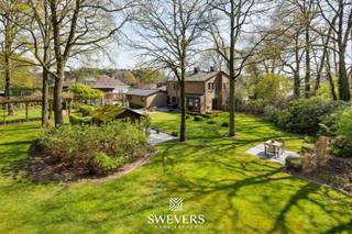 Voor meer info en foto’s, surf naar www.swevers.be – Deze ruime open bebouwing aan de Koerselsesteenweg 146 in Beringen combineert comfortabel wonen met professionele mogelijkheden. Dankzij aparte ingangen voor het privé- en praktijkgedeelte is de woning ideaal voor een zelfstandige activiteit aan huis, maar ook geschikt voor kangoeroewonen. De woning dateert van 1980 en werd doorheen de jaren gericht vernieuwd, met onder meer een nieuw pannendak, gerenoveerde living en keuken, vernieuwde condensatieketel, drie nieuwe Veluxramen en zonnepanelen uit 2023. Met een bewoonbare oppervlakte van 340 m² is er bijzonder veel ruimte. Op het gelijkvloers bevinden zich een woonkamer met eetkamer van samen 46 m², een keuken van 16,40 m², bureau en apart toilet. Het praktijkgedeelte omvat een wachtruimte, consultatieruimte, archief/doka en eigen toilet. Daarnaast zijn er een inpandige garage van 42 m² en een ruime berging. De eerste verdieping telt vier slaapkamers van 12,5 tot 22 m², waarvan één met terras en één met ingemaakte kasten. Verder zijn er een badkamer en apart toilet. De kelder van 44 m² zorgt voor extra bergruimte. Het perceel van 37a 75ca beschikt over een groen aangelegde tuin met meerdere terrassen en tuinhuisjes. Er is parkeerruimte voor 8 à 10 wagens. Scholen, openbaar vervoer en de snelweg zijn vlot bereikbaar. Extra troeven zijn het alarmsysteem, rolluiken, zonnewering en een beveiligde deur. Voor meer informatie, bel 011 255 155. Bron bewoonbare oppervlakte: EPC – verslag.