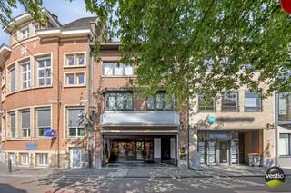 Handelshuis met duplexappartement in hartje Bilzen – Kloosterstraat 2.<br /><br />Deze karaktervolle handelswoning is gelegen op een toplocatie, vlakbij het kerkplein in het bruisende centrum van Bilzen. Het pand bevindt zich op een perceel van 3a 51ca en omvat een verhuurde handelsruimte op het gelijkvloers én een ruim duplexappartement.<br /><br />In 2000 werd het gebouw grondig gerenoveerd, met onder meer een nieuw dak, nieuwe ramen en een volledige binnenafwerking. De nutsvoorzieningen en verwarmingsinstallatie zijn volledig gescheiden voor het handelsgedeelte en de woning.<br /><br /><strong>Handelsruimte:</strong><br />Het handelsgelijkvloers van 160 m² is momenteel ingericht als een stijlvolle delicatessenzaak. De ruimte beschikt over een royale etalage, een ruime handelsruimte, een ingerichte keuken en aparte sanitaire voorzieningen voor dames en heren. De verhoogde en zeer lichtrijke achterzijde van het pand biedt toegang tot een gezellig en uitnodigend tuinterras. De maandelijkse huur bedraagt 1585€/maand.<br /><br /><strong>Duplexappartement:</strong><br />Via het overdekte inkomportaal bereik je het ruime duplexappartement van 158 m².<br />Op het gelijkvloers bevindt zich een aparte inkomhal met een technische ruimte en de CV-installatie. De trap leidt naar de eerste verdieping, waar een inkomhal met gastentoilet en vestiaire toegang geeft tot een lichte leefruimte en een volledig uitgeruste leefkeuken. Grote raampartijen zorgen voor een overvloed aan natuurlijk licht en bieden toegang tot een aangenaam en ruim dakterras.<br />De bovenverdieping beschikt over een nachthal, een praktische wasruimte, twee slaapkamers met uitzicht op de straat, een apart toilet en een comfortabele badkamer met dubbele wastafel, ligbad en douche. Daarnaast is er nog een ruime bergzolder, bereikbaar via de trappenhal, met tal van mogelijkheden.<br /><br /><strong>Belangrijkste troeven zijn:</strong><br />- Gelegen op een uitstekende locatie in het centrum van Bilzen, vlakbij het kerkplein<br />- Combinatie van verhuurde handelsruimte en ruim duplexappartement<br />- Gescheiden nutsvoorzieningen en verwarmingsinstallaties<br />- Twee terrassen: een zonnig dakterras en een sfeervol tuinterras<br />- Karaktervolle gevel en instapklare staat<br />- Ruime zolderverdieping met uitbreidingspotentieel<br />- Asbestveilig<br /><br />Interesse in dit veelzijdige pand?<br />Contacteer ons op 0473 79 29 30 of mail naar luc@vestio.com<br /><br />