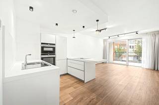 Ontdek dit stijlvolle appartement van circa 84 m², gelegen op de eerste verdieping van een hoogwaardig residentieel gebouw. De woning combineert hedendaagse architectuur met een doordachte indeling en een uitzonderlijk wooncomfort.<br /><br />De inkomhal met vestiaire en apart gastentoilet leidt naar een ruime, lichtrijke leefruimte die naadloos overgaat in de open, volledig ingerichte keuken. Vanuit de leefruimte heeft u toegang tot een zonnig terras van ongeveer 10 m², een aangename plek om te ontspannen of gasten te ontvangen.<br /><br />De royale slaapkamer beschikt over een praktische dressing en geniet bovendien van een eigen terras van 5 m², waardoor u ook hier kunt genieten van een privé buitenruimte. Verder omvat het appartement een stijlvolle badkamer en een afzonderlijke, volledig uitgeruste wasberging.<br /><br />Met een uitstekend EPC-label A biedt deze woning niet alleen comfort, maar ook een hoge energie-efficiëntie. Tal van ingebouwde kasten, aanwezige verlichting en gordijnen verhogen het gebruiksgemak. Daarnaast beschikt u over een private kelderberging, een gemeenschappelijke fietsenstalling en een handige afvalruimte.<br /><br />Een autostaanplaats kan optioneel worden bijgehuurd voor € 190 per maand. De maandelijkse gemeenschappelijke kosten bedragen € 150.<br /><br />Verhuur op naam van een vennootschap is mogelijk. Een instapklaar appartement voor wie op zoek is naar een combinatie van elegantie, functionaliteit en kwalitatief wonen.