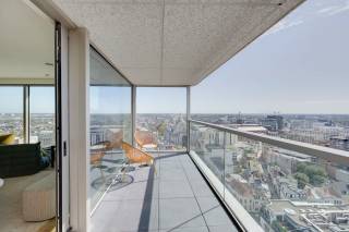 Gelegen in het hart van Antwerpen, aan de De Keyserlei, bevindt zich de iconische Antwerp Tower. Vanuit deze centrale locatie bevinden de Meir, de historische binnenstad, de Opera en het Centraal Station zich op wandelafstand. De Antwerp Tower combineert een bruisende stadsomgeving met een uitzonderlijk wooncomfort en biedt vanuit de hogere verdiepingen een uniek perspectief over de stad.<br /><br />Dit luxueuze appartement op de 19de verdieping, werd stijlvol ingericht door een interieurarchitect en wordt gekenmerkt door zijn panoramische zichten over Antwerpen en een hoogwaardige afwerking. De inkomhal verwelkomt u met ingemaakte kasten en een gastentoilet en beschikt daarnaast over een praktische berging met aansluitingen voor wasmachine en droogkast.<br /><br />Het kloppende hart van het appartement wordt gevormd door de ruime leefruimte met open keuken voorzien van een ruim eiland. Grote raampartijen zorgen hier voor een overvloed aan natuurlijk licht en panoramische vergezichten over de stad. De open keuken vormt een elegant geheel met de zit- en eetruimte en werd uitgerust met kwalitatieve inbouwtoestellen. De mooie parketvloer zorgt voor een warme en stijlvolle uitstraling. Bovendien heeft u hier rechtstreeks toegang tot het zonnige terras, waar u in alle rust kan genieten van de weidse zichten over Antwerpen. Dankzij de aanwezige zonnewering en het ventilatiesysteem type D wordt bovendien ingezet op een aangenaam binnenklimaat en toekomstgericht wooncomfort.<br /><br />De masterbedroom beschikt over ingemaakte kasten en een ensuite badkamer, afgewerkt met hoogwaardige materialen en voorzien van een dubbele wastafel, ruime inloopdouche en toilet. De tweede slaapkamer kan, afhankelijk van uw wensen, eveneens dienstdoen als bureau of multifunctionele ruimte. Beide kamers genieten dankzij hun ligging ook van prachtige zichten over de stad. Een tweede badkamer, uitgerust met een inloopdouche en wastafel, vervolledigt het slaapgedeelte.<br /><br />Tot slot is er een praktische kelderberging, inbegrepen in de prijs. Een ondergrondse garagebox kan bij aangekocht worden voor 65.000 EUR. <br /><br />Wilt u hier binnenkort zelf genieten van deze vergezichten over Antwerpen? Contacteer LISTED voor een bezoek: +32 3 283 51 51.