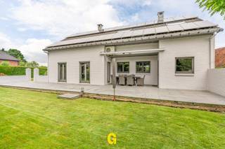 Vlak aan het Pater Vanweertplein te Vlijtingen, deelgemeente van Riemst, bevindt zich deze perfect verzorgde halfopen woning met drie slaapkamers, inpandige garage en fijne tuin op een perceel van 5a 67ca. <br /><br />In deze leuke, autoluwe buurt, net onder de kerktoren van Vlijtingen, ervaart men een aangenaam gevoel van rust en een fijne gemoedelijke sfeer. Tegelijkertijd komt men al snel in het centrum van Riemst met tal van winkels en andere dagelijkse voorzieningen. De basisschool ligt om de hoek. Na een twaalftal minuutjes rijden treft men zowel het centrum van Bilzen als dat van Maastricht. Wie houdt van wandelen, joggen of fietsen in de natuur, kan hier terecht op tal van leuke wandelwegjes, overvloedig te vinden in de nabije omgeving. <br /><br />De woning werd structureel bijzonder degelijk gebouwd eind jaren 80, en daarna voortdurend met de beste zorgen en veel liefde onderhouden. Door de jaren heen mocht dit eigendom een aantal geslaagde renovatie- en verbeteringswerken ondergaan, zoals onder meer de volledige vernieuwing van de leefruimtes en keuken en aantal energetische verbeteringen zoals de installatie van de zonnepanelen. <br /><br />De woning valt op door haar typerende architectuur, terug te vinden in de strakke tijdloze, stijlvolle gevel, als in het interieur, met de open traphal en de aangenaam ingedeelde leefruimtes. Van het niveauverschil tussen de tuin en de weg werd handig gebruik gemaakt, met een inpandige goed toegankelijke garage met berging op de gelijkvloerse verdieping, en aangename lichtrijke leefruimtes op de hogere verdieping, aansluitend op het niveau van het terras en de tuin. <br /><br />INDELING/OMSCHRIJVING:<br /><br />GELIJKVLOERS – niveau van de weg<br />-Inkom met open traphal met handig ingericht bureeltje<br />-Toegang tot de inpandige garage, gelegen op niveau van de weg<br />-Inpandige garage met netjes verzorgde bergruimtes onder volledige woonst en ruimte voor CV<br /><br />1ste VERDIEPING – achteraan uitgevend op niveau van terras en tuin<br />-WC<br />-Knap ingerichte en volledig opgefriste leefruimte met vernieuwde parketvloer en leuke indeling - met eetplaats uitgevend op de tuin, en gezellige zitplaats bij de centrale haard<br />-Ruime aparte kwaliteitskeuken in perfecte staat, hoogwaardig afgewerkt met alle nodige toestellen, ontbijthoek en balkon<br />-Ruime aanpalende berging met praktische inbouwkasten en voorzieningen voor wasplaats<br />-Trap naar de kelder<br /><br />2de VERDIEPING:<br />-Nachthal<br />-Drie volwaardige slaapkamers, waarvan 1 met airco, 1 met inbouwkast<br />-Badkamer met bad en douche, in perfecte staat<br />-Bergruimte<br /><br />BUITEN:<br />-Netjes aangelegd terras, aansluitend op de leefruimte en keuken, deels overdekt en met zonneluifel<br />-Piekfijn verzorgde tuin, op niveau van de leefruimtes, een heerlijke plek om tot rust te komen, of tijd door te brengen met familie of vrienden in de ideale sfeer<br /><br />EPC: 290 kWh/m² p.j. label C – geen renovatieplicht – CV op stookolie – Zonnepanelen 6.290 wp - nog efficiënte verbeteringsmogelijkheden voor wie hier belang aan hecht - Meer info tijdens een bezoek ter plaatse.<br /><br />De kandidaat-koper zal hier een uitstekende verzorgde en instapklare woning terugvinden, met een opvallend degelijke stijlvolle uitstraling zowel binnen als buiten, in een fijne gemoedelijke en gezinsvriendelijke woonomgeving, waar men onmiddellijk welkom zal zijn. Al dan niet kan hier nog verder opgefrist worden voor een nog mooier resultaat, zonder dat dit dringend aan de orde is, gezien de perfecte staat van onderhoud.