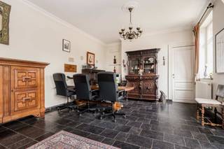 <p><strong>Unieke kasteelvilla met gastenverblijf, siertuin en boomgaard op uitzonderlijk domein</strong></p>
<p>Stap binnen in een wereld van tijdloze klasse en rust in deze magnifieke kasteelvilla, gebouwd in het interbellum en doorheen de jaren zorgvuldig gerenoveerd met oog voor duurzaamheid en authenticiteit. Authentieke elementen zoals trap- en lijstgevels, loden ramen, natuurstenen plinten, erkers, balustrades en een karakteristieke hoektoren geven deze woning haar unieke uitstraling.</p>
<p><strong>Een domein met geschiedenis en karakter</strong><br />Oorspronkelijk opgericht door de eigenaar van een boom- en rozenkwekerij, vind je nog steeds subtiele verwijzingen terug, zoals de sierlijke orchidee verwerkt in de smeedijzeren toegangspoort. Bij het oprijden van de oprijlaan, langs elegante waterpartijen, ervaar je meteen een gevoel van grandeur.</p>
<p><strong>Indeling kasteelvilla</strong><br />Via de majestueuze inkomhal betreed je de eerste sfeervolle leefruimte met open haard, perfect om te onthaasten. Aan de andere zijde van de woning bevindt zich een tweede, lichtrijke woon- en eetkamer met knusse kachel.</p>
<p>Verder is er momenteel een aparte praktijkruimte met wachtruimte en afzonderlijke ingang, ideaal voor vrije beroepen of extra woonfunctie. Aansluitend vind je een vergaderzaal, bureauruimte en atelier, die desgewenst nog kunnen heringericht worden tot een andere functie.</p>
<p>In het souterrain bevindt zich de volledig uitgeruste keuken waarbij het AGA-gasfornuis centraal staat als ware eyecatcher. De aangrenzende eetkamer biedt een intieme sfeer dankzij het lager gelegen niveau. Daarnaast vind je hier ook een wijnkelder, wasruimte en ruime berging.</p>
<p><strong>Verdiepingen</strong><br />Het kasteel beschikt over twee elegante traphallen die leiden naar de bovenverdiepingen. Op de eerste verdieping zijn drie ruime slaapkamers, een dressing en een badkamer met inloopdouche en lavabo. De tweede verdieping heeft vier slaapkamers, waarvan drie met mezzanine, en een tweede badkamer.</p>
<p><strong>Gastenverblijf/conciërgewoning</strong><br />Via de achterbouw bereik je het charmante gastenverblijf met eigen inkom, sanitair en een leef- en slaapruimte op de verdieping – ideaal voor gasten, inwonende hulp of als B&B.</p>
<p><strong>Buitengebeuren</strong><br />Het perceel is een groene oase met aangelegde siertuin, appelboomgaard en speelse graszones. Dankzij de uitgestrekte oppervlakte, de indeling van het domein en de rustige, natuurlijke omgeving is deze eigendom bovendien uitermate geschikt voor het houden van paarden of andere dieren.</p>
<p><strong>Bijzonderheden</strong><br />Deze eigendom straalt luxe en authenticiteit uit dankzij de hoogwaardige afwerking, grote raampartijen en overvloedig natuurlijk licht in elke ruimte. Een ideale thuis voor wie houdt van ruimte, rust en karakter, zonder in te boeten op bereikbaarheid. Opgenomen in inventaris bouwkundig erfgoed.</p>
<p><strong>Ligging</strong><br />Gelegen in een rustige maar levendige buurt met vlotte verbindingen naar E19 en R6. Openbaar vervoer is op wandelafstand, evenals scholen, kinderopvang, winkels, sport- en recreatievoorzieningen.</p>
<p></p>