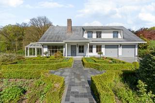 Charmante villa met ruime uitbreidingsmogelijkheden op een uniek privé-domein grenzend aan natuurgebied te Schilde<br /><br />In één van de meest gegeerde en residentiële buurten van Schilde, discreet gelegen aan het einde van een doodlopende straat, bevindt zich deze karaktervolle villa op een uitzonderlijk perceel van ca. 14.990 m², waarvan een deel ingericht werd voor het houden van dieren met eigen verblijf. Een locatie waar rust, privacy, natuurbeleving en comfort naadloos samenkomen.<br /><br />Indeling gelijkvloers:<br />De villa verwelkomt u via een ruime en lichtrijke inkomhal met vestiaire en gastentoilet. Vanuit hier bereikt u de aangename leefruimte met open haard en grote raampartijen, die zorgen voor een prachtig uitzicht op de fraai aangelegde tuin. Aansluitend bevindt zich een sfeervolle leefveranda, volledig omringd door schuiframen en voorzien van automatische zonnescreens, zodat u het hele jaar door geniet van een maximale lichtinval en een harmonieus zicht op het groen.<br /><br />De volledig uitgeruste keuken biedt eveneens zicht op en directe toegang tot het terras en wordt vergezeld door een praktische berging. Aansluitend bevindt zich een tweede gezellige leef- en eetruimte, voorzien van een houtkachel, wat deze ruimte bijzonder warm en uitnodigend maakt. Tevens is er een aparte bureauruimte, ideaal voor wie praktijk- of kantooractiviteiten aan huis wenst. De inpandige garage met automatische poort biedt plaats aan twee voertuigen.<br /><br />Eerste verdieping:<br />De nachthal leidt naar de master bedroom met ensuite badkamer, aangevuld met drie comfortabele, volwaardige slaapkamers. Daarnaast is er een tweede badkamer met douche en een bijzonder ruime, functionele wasplaats.<br /><br />Tuin en buitenbeleving:<br />De zuidwest-georiënteerde parktuin vormt een ware oase van rust, met weidse vergezichten en een bijzonder harmonieuze groenbeleving. De tuin werd smaakvol aangelegd, inclusief een fraaie vijverpartij, en beschikt bovendien over een bijgebouw/stal voor het houden van dieren — ideaal voor paarden- of dierenliefhebbers, of voor wie een hobbyproject wenst te realiseren.<br /><br />Bijzonderheden:<br />- Maximale privacy, prestigieuze ligging &amp; ideale zonoriëntatie<br />- Renovaties: 1997 (aanbouw leefruimte) – 1999 (gedeeltelijk buitenschrijnwerk)<br />- Verwarming op aardgas (Viessmann) via radiatoren en convectoren<br />- Dubbele beglazing (hout &amp; aluminium)<br />- Rolluiken aanwezig<br />- Videofonie &amp; automatische toegangspoort<br />- Oprit met plaats voor ca. 6 wagens<br />- Bergzolder toegankelijk via vlizotrap