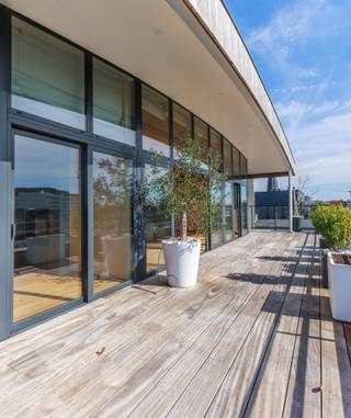 <span>In Residentie Azimuth vindt u dit uitzonderlijk </span><strong>ruim en exclusief dakappartement</strong><span> op de zesde verdieping. Deze </span><strong>penthouse</strong><span> kenmerkt zich door een sublieme combinatie van ruimte, licht en doordachte architectuur. U geniet hier van een formidabel </span><strong>panoramisch uitzicht</strong><span> over de stad Gent, met aan de achterzijde een prachtig zicht op de iconische Gentse torens.</span><br /><span>De indeling werd bijzonder doordacht uitgewerkt door architect </span><strong>Luc Vertongen</strong><span> en centreert zich rond de </span><strong>royale leefruimte</strong><span> met aansluitend een ruim </span><strong>zonneterras</strong><span>. Grote glaspartijen zorgen voor een sterke connectie tussen binnen en buiten en laten het natuurlijke licht overvloedig binnenstromen. De leefruimte omvat een elegante zithoek met doorkijkhaard en een sfeervolle eethoek, afgewerkt met een parketvloer in 3 cm dikke eik, afkomstig uit Franse treinwagons, wat het geheel een warme en karaktervolle uitstraling geeft. Aansluitend bevindt zich een volledig ingerichte keuken die perfect aansluit bij het stijlvolle geheel.</span><br /><span>Het </span><strong>riante terras</strong><span> van ca. 66 m², uitgevoerd in tropisch hout, omarmt het appartement en biedt verschillende plekken om te genieten van zon, rust en het uitzicht over de stad. Een uitzonderlijk terras waar ruimte en het stadsleven naadloos samenkomen.</span><br /><span>Het appartement beschikt over </span><strong>drie slaapkamers</strong><span>, waaronder een master bedroom met </span><strong>dressing</strong><span> en een </span><strong>eigen badkamer</strong><span>, uitgerust met ligbad en toilet. Daarnaast is er een tweede </span><strong>badkamer</strong><span> met douche en toilet, evenals een </span><strong>gastentoilet</strong><span>, een aparte </span><strong>berging/wasplaats</strong><span> en een praktische </span><strong>vestiaire</strong><span>. De ruime </span><strong>garagebox</strong><span> op niveau -1 met plaats voor twee wagens, extra bergruimte én een laadpunt voor elektrische wagens is inbegrepen in de vraagprijs.</span><br /><span>Met een bewoonbare oppervlakte van ca. 150 m², een terras van ca. 66 m² en een hoogwaardige materiaalkeuze vormt dit dakappartement een uitzonderlijke kans voor wie op zoek is naar exclusiviteit, ruimte en een bijzondere woonbeleving in Gent.</span>