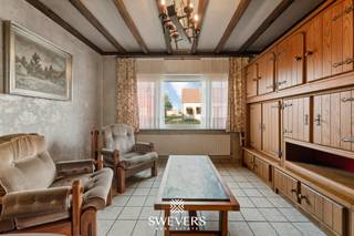 Voor meer info en foto’s, surf naar www.swevers.be – Deze vrijstaande woning in Houthalen biedt een uitstekende basis voor wie op zoek is naar ruimte, potentieel en een gunstige ligging. De woning uit 1957 ligt op een zuidelijk georiënteerd perceel van 13a18ca in een rustige wijk, op wandelafstand van winkels, horeca, openbaar vervoer en met vlotte verbinding naar de snelwegen. Met een bewoonbare oppervlakte van 180 m² is dit pand ideaal voor renovatie naar eigen smaak. Op het gelijkvloers vind je een eetkamer aansluitend op de woonkamer, een veranda, een centrale keuken, een functionele badkamer, apart toilet en ruime berging. Boven zijn er drie slaapkamers (16,38 m², 12,64 m² en 7,93 m²) en een aparte bureauruimte. De woning beschikt over een kelder bereikbaar via de keuken, langs buiten twee garages en achter in de tuin een werk- of hobbyruimte. De zuidgerichte tuin is een grote troef voor buitenliefhebbers. Voor meer informatie, bel 011 255 155. Bron bewoonbare oppervlakte: EPC – verslag.
