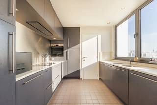 <p>Een ruim en lichtrijk duplex-appartement met een uniek karakter, gelegen op de bovenste verdiepingen van een modern gebouw. Deze woning combineert stedelijk wooncomfort met een opmerkelijk terras en een weids panoramisch uitzicht over de stad.</p>
<p>De woonkamer op houten vloer met kamerhoge raampartijen biedt ruimte voor zowel een comfortabele zithoek als een volwaardige eethoek. Aansluitend aan de eethoek bevindt zich een separate, ingerichte keuken met ingebouwde apparatuur. Een raam geeft ook hier zicht op de stad — koken wordt een aangenaam moment.<br />Op de leefverdieping bevindt zich een eerste ruime slaapkamer met aansluitend badkamer. Een stalen trap met houten treden verbindt de woonverdieping met de bovenste verdieping waar zich twee bijkomende slaapkamers en een badkamer bevinden. <br /><br />Wie droomt van buitenleven in de stad, vindt hier zijn gading. Het ruime terras biedt een panoramisch zicht over het Theaterplein, compleet met zithoek en eettafel. De perfecte plek voor een aperitief bij zonsondergang of een ontspannen weekendochtend.</p>
<p>Het gebouw is uitstekend gelegen in de nabijheid van de Antwerpse binnenstad, winkels, horeca en openbaar vervoer. <br />Twee autostaanplaatsen worden te koop aangeboden voor 50.000 euro per plaats.</p>