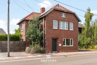 Voor meer info en foto’s, surf naar www.swevers.be – instapklare open bebouwing met 190 m² bewoonbare oppervlakte op een perceel van 5a12ca in de Kerkstraat 15 te Nieuwerkerken. De woning dateert van 1948, werd volledig gerenoveerd in 2012 en kreeg in 2021 een nieuwe keuken en een stijlvolle sfeerhaard. Dankzij de doordachte indeling, grote raampartijen en overvloedige lichtinval geniet u hier van een aangenaam wooncomfort. Op het gelijkvloers vindt u een ruime woonkamer, een gezellige eetkamer, een moderne keuken met veel werk- en bergruimte, een praktische berging en een gastentoilet. De eerste verdieping beschikt over twee ruime slaapkamers, waarvan één met ingebouwde kasten, een badkamer met aansluitende dressing, een apart toilet en een handige wasvoorziening. Via een vaste trap bereikt u de tweede verdieping, waar een hobby ruimte van 36 m² tal van mogelijkheden biedt als master bedroom. Daarnaast is er een kelder van circa 6 m². Buiten geniet u van een zonnige, zuidwestgerichte tuin met fruitbomen, een ruim terras en een overdekt terras. Vooraan is parkeergelegenheid voor drie wagens. Extra troeven zijn de airconditioning, tien zonnepanelen met groenestroomcertificaten en de energiezuinige voorzieningen. De ligging is eveneens een pluspunt, met openbaar vervoer op 100 meter, winkels, scholen en horeca op ongeveer 2 kilometer, een vlotte verbinding naar de snelweg en het Provinciaal Domein Nieuwenhoven op slechts 6 kilometer. Een ideale woning voor wie op zoek is naar ruimte, comfort en een rustige, centrale ligging. Voor meer informatie, bel 012 699 900. Bron bewoonbare oppervlakte: EPC – verslag.