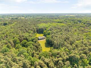 Langs een statige oprijlaan, volledig omgeven door groen, bereiken we deze uitzonderlijke eigendom die zich ontvouwt als een ware oase van rust. Op een indrukwekkend perceel van maar liefst 8,4 hectare geniet u hier van absolute privacy, ruimte en sereniteit. Ondanks de uiterst rustige ligging is er toch een vlotte verbinding met de E313 richting Antwerpen of Hasselt.<br /><br />Gelijkvloers:<br />We betreden de woning via een ruime inkomhal met gastentoilet. Rechts bevindt zich een royaal bureau met bibliotheek en een aparte zithoek, ideaal als rustige werk- of leesruimte. Vanuit de hal komen we in de lichtrijke woon- en eetkamer met parketvloer en open haard. Deze leefruimte geeft rechtstreeks toegang tot het ruime terras, waar u een prachtig uitzicht heeft over de tuin en de omliggende natuur.<br />Aansluitend aan de woonkamer bevindt zich de ingerichte keuken, uitgerust met oven, elektrisch fornuis en dampkap. Ook deze ruimte biedt toegang tot het overdekte terrasgedeelte. Verder beschikt deze vleugel over een praktische wasplaats.<br /><br />Tussenverdieping:<br />Op de overloop bevindt zich een eerste ruime slaapkamer met lavabo, perfect als gastenkamer of polyvalente ruimte.<br /><br />Verdieping:<br />Rechts van de nachthal vinden we de eerste badkamer, voorzien van douche, ligbad en dubbele lavabo. Aansluitend is er een ruime dressing. In dit gedeelte bevinden zich tevens twee ruime slaapkamers op tapijtvloer en een apart toilet.<br />Aan de linkerkant van de nachthal leidt een deur naar het tweede deel van de verdieping, waar zich de masterbedroom bevindt met aansluitend de tweede badkamer. Deze is uitgerust met ligbad, douche, dubbele lavabo en een apart toilet.<br /><br />Dankzij de uitzonderlijke ligging, de royale ruimtes en de veelzijdige indeling biedt deze woning tal van mogelijkheden. Ideaal voor wie op zoek is naar ruimte, privacy en wonen in het groen.