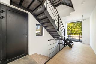 Indeling<br /><br /><strong>Gelijkvloers - eerste verdieping<br /></strong><br />Bij het betreden van dit stijlvolle duplexappartement wordt u verwelkomd in een royale inkomhal, waar de karaktervolle industriële trap meteen de toon zet. Op deze verdieping bevinden zich tevens een zeer ruime was-/bergruimte en een gastentoilet.<br /><br />De lichtrijke leefruimte straalt warmte en elegantie uit dankzij de hoogwaardige stenen vloer met houtlook, die naadloos doorloopt in de open leefkeuken. Deze luxueuze keuken werd uitgerust met kwalitatieve Bosch- en AEG-toestellen, een royaal kookeiland en een ruim werkblad. Vanuit de keuken geniet u bovendien van een prachtig groen zicht op de tuin.<br />Aansluitend bevindt zich het ruime dakterras, waar binnen- en buitenleven harmonieus in elkaar overvloeien. Via een buitentrap bereikt u de diepe privatieve tuin.<br /><br />Verder beschikt deze verdieping over een ruime master bedroom met een stijlvolle en-suite badkamer, uitgerust met een royale inloopdouche, dubbele wastafel en toilet.<br /><br /><strong>Tweede verdieping<br /></strong><br />Op de bovenverdieping bevinden zich nog twee volwaardige slaapkamers. Deze delen een tweede, smaakvol afgewerkte badkamer met inloopdouche en wastafel, aangevuld met een apart toilet.<br /><br />Achteraan het gebouw geniet u van twee privatieve autostaanplaatsen, vlot bereikbaar via een aparte inrit.<br /><br />Tot slot beschikt het appartement over een droge privatieve kelderberging, ideaal als extra opslagruimte.<br /><br />Bijzonderheden:<br />B-label, koelinstallatie via lucht-lucht warmtepomp, verwarming radiatoren via cv gas, videofoonsysteem in elke ruimte, zwarte aluminium ramen, Vg-Wg-Gvv-Gvkr-Gmo