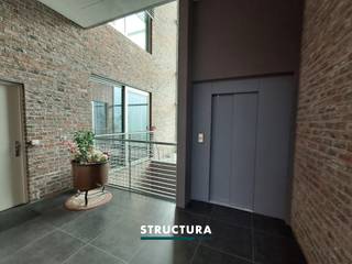 In het centrum van Merchtem bevindt zich deze ruime loft met een bewoonbare oppervlakte van ca. 133 m², ondergebracht in de voormalige Azijnbrouwerij. Het industriële karakter van het gebouw is mooi bewaard gebleven en komt onder meer tot uiting in de hoge plafonds, de authentieke plafondstructuur en de grote raampartijen.De leefruimte vormt het hart van de loft en combineert een open karakter met veel natuurlijke lichtinval. De gashaard zorgt voor extra sfeer en sluit mooi aan bij de industriële uitstraling van het geheel. Met drie slaapkamers, een EPC-label B en een centrale ligging biedt deze loft bovendien een interessante combinatie van ruimte, karakter en energiezuinigheid.IndelingEerste verdieping: Inkomhal met apart toilet, ruime en lichtrijke leefruimte, open keuken, terras, drie slaapkamers, douchekamer en badkamer met zowel bad als douche. Gelijkvloers: garage, bij aan te kopen aan €25.000 Karakteristieken- EPC-label B- Momenteel verhuurd aan € 1.175/maand- Centrale ligging in Merchtem- Zuid georiënteerd terrasEen karaktervolle loft waar de geschiedenis van het gebouw nog duidelijk voelbaar is, gecombineerd met een ruime indeling en hedendaags wooncomfort. Dankzij de drie slaapkamers, de oppervlakte van ca. 133 m² en het gunstige EPC-label B is dit een interessante eigendom voor wie op zoek is naar een ruime loft in het centrum van Merchtem. Contacteer ons via 02 460 80 46 of info@structura.be