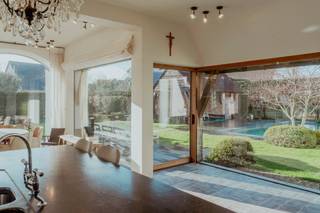 Beleef de perfecte symbiose tussen traditie en luxe in deze villa (2017), ontworpen door architect Stéphane Boens. Gelegen op een zonovergoten perceel van ca. 1.000 m² in een rustige residentiële wijk, bevindt u zich op wandelafstand van de zee en het centrum van Koksijde. De woning combineert klassiek vakmanschap, zoals metselwerk in wildverband, afgeronde muren, unieke raamopeningen die het daglicht prachtig naar binnen gidsen en smeedijzeren details, met hedendaagse luxe. Een uniek eigendom waar authentiek vakmanschap en modern wooncomfort op hoog niveau samenkomen.Het private gedeelte omvat een leefruimte met open haard, een luxueuze leefkeuken met gashaard voorzien van panoramisch zicht op de tuin en een master-suite die beschikt over een eigen luxebadkamer met bad, douche en dubbele lavabo op het gelijkvloers. Op de verdieping bevinden zich nog twee slaapkamers met badkamer en een polyvalente ruimte die naar wens kan dienen.Het B&B-gedeelte beschikt over een eigen inkom, een sfeervolle eetruimte en drie gastenkamers met elk een ensuite badkamer. Dankzij de praktische indeling kan dit gedeelte bovendien perfect worden ingericht als volwaardig privatief woongedeelte. De zuidwestelijk georiënteerde tuin is een oase van rust, waar u het hele jaar door geniet van maximale zoninval. Het middelpunt is het schitterende zwembad (7 x 3,5 m). Voor de ultieme ontspanning kunt u afdalen naar de kelderverdieping, die is ingericht als een volwaardige wellness met een sauna, hamam, douche en toilet.Benieuwd naar deze villa? Plan dan in uw afspraak in bij Carl Boedts (0473/951821) of Yari Devos (0491/272185).