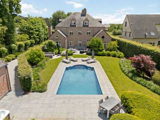 At the end of a dead-end street, we find this luxurious manor with, among other things, 4 bedrooms, 3 bathrooms, a heated swimming pool, and a large outbuilding on a spacious plot of approximately 2,673 m².<br /><br />Layout ground floor:<br />Through the spacious entrance hall with guest toilet, cloakroom, and stately staircase, we enter the living area. This consists of a spacious TV room, a seating area with a cozy fireplace, and a very bright dining room. Next, we reach the spacious kitchen with a professional Lacanche stove, many MIELE appliances, an island, and space for a breakfast nook. Furthermore, this kitchen gives us access to a nice and very bright family room with a fireplace and a beautiful view of the landscaped garden and pool. Also, a very spacious and practical utility room with space under the counter for the washing machine and dryer, custom cabinets, and space for an extra wine cooler, freezer, and refrigerator.<br /><br />First floor:<br />Through the large central landing, we reach the master suite with bedroom 1, a large dressing room, and a luxurious bathroom. Furthermore, the 2nd and 3rd bedrooms and the 2nd luxury bathroom, equipped with a shower, bath, double sink, and toilet.<br /><br />Second floor:<br />Through the fixed staircase, we reach this full extra floor. Here we find a 4th bedroom and 3rd bathroom. Furthermore, we also find an extra living room which can also be used as an extra 5th bedroom. The possibility of connecting an extra kitchen or 4th bathroom has been provided.<br /><br />Basement:<br />The staircase finished with travertine brings us to the full floor. This has been beautifully finished and consists of a wine cellar with brick niches and a separate technical room with the central heating system, etc.<br /><br />Outbuilding:<br />At the back of the garden, we find the spacious outbuilding, completely in the same architecture as the villa, currently used as a garage, pool house, storage, and also has a spacious first floor.<br /><br />SPECIAL FEATURES<br />- Extensive alarm system<br />- Charging station<br />- Automated gates with access control and video intercom<br />- The entire villa is equipped with air conditioning/heat pump<br />- Water softener<br />- Finished with top-quality materials!