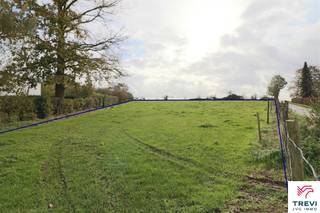 Grand et beau terrain à bâtir, de configuration plane, de +/- 59 ares sis en zone d'habitat à caractère rural. Façade de +/- 30 m (zone de recul à...