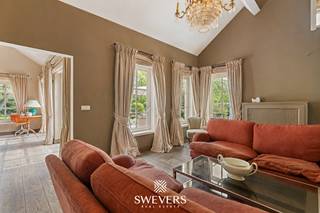 Voor meer info en foto’s, surf naar www.swevers.be – Deze open bebouwing op Laan op Heusden 47 in Koersel werd gebouwd in 2006 en biedt met een bewoonbare oppervlakte van 256 m² heel wat ruimte en mogelijkheden. De woning is op te frissen, maar beschikt over een doordachte indeling en een sterke basis om er een eigentijdse en warme thuis van te maken. Op het gelijkvloers kom je binnen via de inkomhal met gastentoilet. Centraal ligt de eetkamer, met aansluitend een aparte living van 18,90 m² met houthaard. De ruime keuken van 28,30 m² biedt plaats voor een eethoek, is uitgerust met een gashaard en geeft rechtstreeks uit op terras en tuin. Verder zijn er een wasplaats, een slaapkamer van ca. 15 m², een dressing, een badkamer met ligbad en dubbele lavabo en een aparte tuinkamer van 14,50 m² met gashaard. Op de verdieping zijn er nog 2 ruime slaapkamers van ca. 20,43 m² en 22,19 m², een tweede badkamer en een mooie vide met ingerichte bibliotheek. Extra bergruimte is er via inbouwkasten en de zolder. Het perceel heeft een oppervlakte van 2876 m², waarvan de bouwgrond bestaat uit 7a55ca. Buiten geniet je van een private noordoostgerichte tuin met bekabeling voor tuinverlichting. Bijkomende troeven zijn de regenwaterput van 5.000 liter, voorbereiding voor luidsprekers en een recent onderhouden ketel. Rustig gelegen, met scholen, winkels, openbaar vervoer en ontspanning in de nabije omgeving en een vlotte verbinding naar de snelweg. Voor meer informatie, bel 011 255 155. Bron bewoonbare oppervlakte: EPC – verslag.
