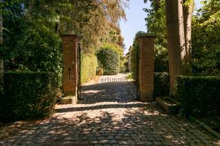 <p><span>Statige klassieke villa op ca. 2.450 m² in een gegeerde residentiële dreef te Schoten</span></p><p><span>Op een uitzonderlijk ruim perceel van circa 2.450 m² bevindt zich deze karaktervolle villa met ongeveer 400 m² bewoonbare oppervlakte. De woning combineert een imposante uitstraling met royale leefruimtes, vijf slaapkamers, twee badkamers en een volledig omringende tuin. Een unieke eigendom voor wie op zoek is naar ruimte, privacy en renovatiepotentieel op een uitstekende locatie.</span></p><p><span>Via de representatieve inkomhal met vestiaire en gastentoilet betreedt u de woning. De leefruimte is afgewerkt met parket en wordt gekenmerkt door een grote, imposante haard die meteen de aandacht trekt. Hoge plafonds en de opgehoogde inplanting versterken het statige karakter.</span></p><p><span>De witte keuken is volledig ingericht en sluit aan op een praktische bijkeuken met een tweede toilet en rechtstreekse toegang tot de tuin. Vanuit de inkomhal is ook de ruime garage voor twee wagens bereikbaar, voorzien van een automatische poort. Op het gelijkvloers beschikt de woning over dubbele beglazing en rolluiken.</span></p><p><span>De verdieping omvat vijf ruime, verwarmde slaapkamers, twee badkamers en een afzonderlijk toilet. Ook hier zorgen de hoge plafonds voor een bijzonder aangenaam ruimtegevoel. De houten ramen op deze verdieping zijn momenteel nog voorzien van enkele beglazing.</span></p><p><span>De woning is volledig onderkelderd en uitgerust met een alarmsysteem. De centrale verwarming werkt op mazout; de huidige installatie is ouder en dient op termijn te worden vernieuwd.</span></p><p><span>Rondom de villa ligt een royale tuin met meerdere terrassen en tal van mogelijkheden. Dankzij de omvang van het perceel geniet u hier van veel privacy, groen en ruimte voor ontspanning.</span></p><p><span>De woning werd steeds goed onderhouden. Een grondige opfrissing en energetische renovatie zijn aangewezen. Dit biedt de toekomstige eigenaar de kans om deze statige villa volledig naar eigen smaak en hedendaagse normen te vernieuwen.</span></p><p><span>Een unieke opportuniteit voor wie droomt van een royale, klassieke villa op een toplocatie en deze wil transformeren tot een eigentijdse gezinswoning.</span></p>