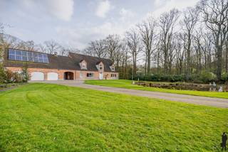 <p><strong>Riante gerenoveerde pastorijwoning met garage, studio en wellness op een perceel van ca. 5.400 m²</strong></p>
<p>Deze prachtige pastorijwoning werd volledig gerenoveerd en is gelegen op een ruim en privatief perceel van ca. 5.400 m². De woning combineert karakter met hedendaags comfort en beschikt over 4 à 5 slaapkamers, 3 badkamers, een ruime garage met studio en een aangelegde tuin met wellness.</p>
<p>De woning omvat:</p>
<ol>
<li>Een gelijkvloerse verdieping met o.a. inkomhal, leefruimte, open keuken, bureel/slaapkamer en badkamer.</li>
<li>Een eerste verdieping met meerdere slaapkamers en badkamers.</li>
<li>Een garagegebouw met studioverdieping.</li>
</ol>
<p><strong>Voorzieningen op het gelijkvloers:</strong><br />Deze woning is op het gelijkvloers voorzien van:<br />- Een ruime inkomhal op parket met vestiairekast en gastentoilet met handenwasser<br />- Een eerste slaapkamer met ensuite badkamer voorzien van inloopdouche, toilet en lavabo<br />- Een tweede kamer, ideaal als bureel of extra slaapkamer.<br />- Een lichtrijke leefruimte met open haard en grote schuiframen met toegang tot de tuin.<br />- Een open, volledig ingerichte keuken met o.a. dubbele spoelbak, vaatwasser, gasfornuis met oven, dampkap, Amerikaanse koelkast en wijnkoelkast.</p>
<p><strong>Voorzieningen op de eerste verdieping:</strong><br />De eerste verdieping bestaat uit:<br />- Twee ruime slaapkamers.<br />- Een badkamer met douche, toilet en lavabo, alsook aansluitingen voor wasmachine en droogkast.<br />- Een master bedroom met dressing en ensuite badkamer voorzien van ligbad, inloopdouche, dubbele lavabo en toilet.<br />- Twee praktische bergruimtes op de overloop.</p>
<p><strong>Garage en studio:<br /></strong>- Ruime inpandige garage met automatische poorten en plaats voor drie wagens.<br />- Boven de garage bevindt zich een studioverdieping, bereikbaar via een vaste trap.</p>
<p><strong>Tuin:</strong><br />Aangelegde en privatieve tuin bereikbaar via een automatische toegangspoort en lange oprit met parkeermogelijkheden voor meerdere wagens. De tuin beschikt over een siervijver met terras, een open achterliggend perceel met mooie bomen, een overdekt terras, een aanbouw met glaspartijen en een buitenwellness met sauna, douche en koelbad.<br />Tussen de woning en de garage bevindt zich een overdekte carport.</p>
<p><strong>Extra troeven:<br /></strong>- Zeer ruim perceel met veel privacy<br />- Groot bewoonbaar volume<br />- Drievoudige garage<br />- Veel lichtinval<br />- Kruipruimte onder de volledige woning<br />- Gunstig EPC</p>