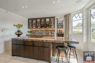 met veel oog voor detail. 
Indeling: inkomhal met vestiaire en gastentoilet, prachtige keuken met ontbijthoek, praktische bijkeuken, ruime eetkamer aansluitend op de living met houthaard. 
Alle leefruimtes geven uit op het terras met zonneluifel en op de prachtig aangelegde tuin. 
1ste verdieping: zeer ruime master bedroom met prachtige zichten en met dressing, bureau en badkamer. Tweede slaapkamer met douchekamer. 
2de verdieping: derde slaapkamer met een badkamer, vierde slaapkamer met bergruimte. Apart toilet, technisch lokaal. 
Inpandige garage en staanplaatsen voor 4 wagens. Magnifieke tuin aangelegd door Stijn Cornilly. 
EPC: 103,50 kWh/m² - UC: 31043-G-2012_42/EP14854/A002/D01/SD001