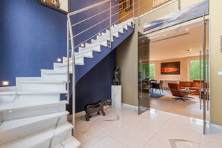 Deze exclusieve, vrijstaande villa in landelijke stijl in Wemmel straalt pure klasse uit. Met een royale bewoonbare oppervlakte van 526 m² en een superieure afwerkingsgraad geniet u hier van uitzonderlijk wooncomfort. De zandkleurige gevel combineert harmonieus met charmante dakkapellen en een monumentale glaspartij bij de inkom. De woning is energie-efficiënt uitgerust met zonnepanelen en een hoogwaardig alarmsysteem.<br /><br />De villa ligt op een discreet perceel, volledig aan het oog onttrokken via een lange privé-inrit. Dit garandeert honderd procent privacy en sereniteit, terwijl scholen, openbaar vervoer en de Brusselse Ring (R0) vlakbij zijn.<br /><br />Binnen opent de inkomhal in een spectaculaire vide met een marmeren trappartij. De centrale leefruimte ademt licht dankzij kamerhoge schuiframen naar de tuin. De living beschikt over een formele eethoek, een zithoek met maatwerkkasten en een sfeervol tweede salon met gashaard. Daarnaast is er een onafhankelijke praktijk- of kantoorruimte op het gelijkvloers.<br /><br />De high-end leefkeuken met werkeiland en premium Miele-apparatuur sluit naadloos aan op het terras. Op de verdieping biedt de mezzanine toegang tot vier grote slaapkamers met ingebouwde kasten en drie stijlvolle, moderne badkamers. De master suite beschikt over een eigen dakterras.<br /><br />De prachtig aangelegde tuin is omzoomd door hoge hagen en beschikt over een strak buitenzwembad met hardhouten zonneterrassen. Aan de voorzijde biedt de oprit plaats voor een tal van wagens.<br /><br />Bestuursmaatregelen in het maatregelenregister: nee
