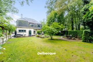 Maak kennis met deze karaktervolle doch op te frissen villa van 1939 ontworpen door architect H. Verbruggen, opgebouwd in de interbellumstijl, en gelegen op een ruim perceel aan de rand van een gegeerde villawijk in Sint-Kruis vlakbij scholen, winkels, station, ziekenhuis, centrum Brugge, ontspaningsmogelijkheden,... <br />De unieke en authentieke uitstraling van de villa gecombineerd met de groene omgeving maakt deze woonst dan ook erg bijzonder. <br /><br />De villa werd door de huidige eigenaars in 1990 uitgebreid tot een woning met praktijkgedeelte (die perfect kan dienen als bureel of kangoeroewoning). Dit praktijk/kangoeroegedeelte heeft een afzonderlijke praktische ingang. <br />De hoofdwoning dient op bepaalde aspecten wel terug gemoderniseerd te worden om terug aan het hedendaags wooncomfort te kunnen voldoen. <br /><br />De villa betreden we via een statige en ruime inkomhal met authentieke trap. Verder begeven we ons naar de riante leefruimte opgesplitst in verschillende zithoeken die van elkaar afgescheiden zijn via authentieke boogstructuren, een naastgelegen afzonderlijke eetplaats en keuken. <br />Voorts vinden we op de gelijkvloerse verdieping nog een doorgang terug naar het bijgebouwde praktijk/bureelgedeelte. Daar vinden we nog een apart toilet terug, kitchenette, douchekamer en een leefruimte/bureelruimte of ruimte die kan dienen als extra leefruimte/kangoeroewoning. <br /><br />Op de eerste verdieping vinden we 4 slaapkamers terug (waarvan masterbedroom met annex dressing/bureau) en een badkamer. <br />Op de tweede (zolder)verdieping vinden we nog een 5e slaapkamer of polyvalente kamer terug die te bereiken is via een vaste trap. <br /><br />Deze villa beschikt naast de riante achtertuin tevens over een mooi aangelegde voortuin met afzonderlijke toegang tot het praktijk/bureelgedeelte, alsook een parking voor wagens en oprit naar achteren met carport.<br /><br />Kortom: een zeldzame en ruime villa gelegen op een uiterst gegeerde en strategische locatie. Contacteer ons snel voor een bezoek aan dit eigendom via info@delbecque.immo of 050 45 03 45