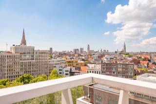 Op een indrukwekkende negende verdieping van een recent residentieel gebouw bevindt zich dit elegant appartement van ca. 110 m², aangevuld met een aangenaam terras van ca. 11 m². De uitzonderlijke ligging en hoogte staan garant voor een weids panoramisch uitzicht over Antwerpen, waarbij onder meer het MAS, de Onze-Lieve-Vrouwekathedraal en de Boerentoren het unieke stadsdecor bepalen.

Via de ruime inkomhal wordt de leefruimte bereikt, waar grote raampartijen zorgen voor een overvloed aan natuurlijk licht en een voortdurende connectie met de skyline van de stad. De open keuken sluit naadloos aan op de leefruimte en beschikt aansluitend over een praktische berging.

Het slaapgedeelte omvat twee ruime slaapkamers, een stijlvolle badkamer en een nachthal met afzonderlijk gastentoilet en extra bergruimte.

De afwerking combineert warme parketvloeren in de leef- en slaapvertrekken met onderhoudsvriendelijke tegelvloeren in de keuken en sanitaire ruimtes, wat het geheel een tijdloze en verzorgde uitstraling geeft.

Als verlengde van de leefruimte biedt het terras van ca. 11 m² een bijzondere buitenruimte waar men in alle rust kan genieten van het panoramische zicht over de stad.

Een privatieve parkeerplaats op niveau -3 is mee aan te kopen voor € 35.000.

Momenteel is het appartement verhuurd.

De residentie bevindt zich op een uitzonderlijke locatie tussen 't Eilandje en het historische stadscentrum. Deze stadsomgeving combineert een vlotte bereikbaarheid met een ruim aanbod aan winkels, restaurants, hotspots en culturele voorzieningen.
