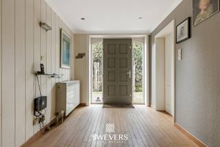 Voor meer info en foto’s, surf naar www.swevers.be – Aan de Hulsbergweg 14 in Zonhoven bevindt zich deze open bebouwing op een ruim perceel van 795 m². De woning werd gebouwd in 1976, heeft een bewoonbare oppervlakte van 180 m² en beschikt over een praktische, volledig gelijkvloerse indeling. Ideaal voor wie op zoek is naar een woning met potentieel die naar eigen smaak kan worden opgefrist. De ruime woonkamer van 44,45 m² biedt voldoende plaats voor een gezellige zit- en eethoek en sluit aan op de veranda met zicht op de tuin. De afzonderlijke keuken van 15,15 m² biedt heel wat mogelijkheden voor een functionele inrichting. Verder zijn er drie slaapkamers van 12 m², 16 m² en 12,25 m². Een bijkomende kamer kan perfect dienstdoen als bureau, hobby- of speelkamer. De badkamer is uitgerust met een bad, wastafel en toilet. Daarnaast is er nog een afzonderlijk toilet aanwezig. Extra opbergruimte vind je in de kelder van 15 m². Een grote troef is de vrijstaande dubbele garage van maar liefst 50 m², ideaal voor wagens, fietsen, tuinmateriaal of een werkhoek. De ruime tuin rondom de woning biedt volop mogelijkheden om van het buitenleven te genieten. Openbaar vervoer en de snelweg bevinden zich bovendien op korte afstand, terwijl scholen, winkels en ontspanning vlot bereikbaar zijn. Voor meer informatie, bel 011 255 155. Bron bewoonbare oppervlakte: EPC – verslag.