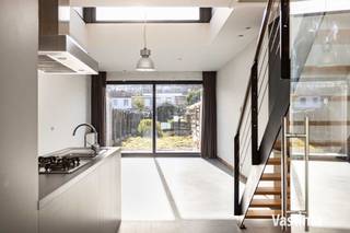 Al een hele poos op zoek naar een betaalbare stadswoning met tuin? Liefst geen oude woning, maar een recenter exemplaar? Dan is deze woning precies wat je zoekt. <br /><br />Deze woning werd gebouwd in 2002 en is ontworpen met het oog op singles, jonge koppels en kleine gezinnen die comfortabel willen wonen zonder de lasten van een grote woning. Compact waar het kan, verrassend ruim waar het moet en het perfecte alternatief voor een appartement! <br /><br />Al bij het binnenkomen merk je dat over de indeling goed is nagedacht. Vooraan beschik je over een handige berg- en fietsenruimte. Geen gedoe meer met fietsen, afval of boodschappen die door de leefruimte moeten. Een klein detail dat elke dag opnieuw een groot verschil maakt. <br /><br />De absolute blikvanger van de woning is zonder twijfel de leefruimte met open keuken. Dankzij de verhoogde dakuitbouw met zijn extra zijramen baadt deze ruimte de hele dag in natuurlijk licht. Het resultaat? Een heerlijk ruimtegevoel dat je van buitenaf nooit zou verwachten. De volledig uitgeruste keuken vormt samen met de leefruimte het hart van de woning. En dankzij de grote raampartij, geniet je bovendien de hele dag door van licht en zicht op je tuin. Verder beschik je op het gelijkvloers over een gastentoilet met handenwasser. <br /><br />Op de eerste verdieping bevinden zich een ruime slaapkamer met aansluitende dressing en een verzorgde badkamer met douche in bad en toilet. Onder het dak vind je nog een tweede slaapkamer en een technische ruimte met extra stockagemogelijkheden. <br /><br />Ook technisch zit je hier helemaal goed. De woning beschikt over een zonneboiler voor warm water in combinatie met een CV op gas, een regenwaterput van 5.000 liter, een conforme elektrische installatie en is volledig asbestvrij. Bovendien geldt er geen renovatieverplichting, waardoor je zonder zorgen kunt verhuizen. <br /><br />Achteraan wacht een gezellige stadstuin met terras waar je na een drukke dag heerlijk tot rust komt.  <br /><br />De woning vraagt hier en daar nog een persoonlijke afwerking, maar net dat biedt je de kans om ze volledig naar jouw smaak af te werken en er écht je eigen thuis van te maken. <br /><br />Ligging is nog een extra troef: rustig, maar toch vlak bij centrum Aalst. Scholen, winkels, openbaar vervoer en grote verbindingswegen bevinden zich op korte afstand. Parkeren doe je vlot op de vele voorbehouden bewonersplaatsen in de straat. <br /><br />Een recente stadswoning met tuin, veel licht, een doordachte indeling en moderne technieken kom je niet elke dag tegen. Benieuwd of dit jouw nieuwe thuis wordt? Contacteer Vastima vandaag nog en plan snel je bezoek! 