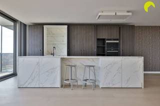 Helemaal op het einde van de Fruithoflaan vinden we in residentie "Nirvana" dit volledig gerenoveerd 2 slaapkamer appartement van circa 147 m² op de 11de verdieping. Als jij graag hoog woont en houdt van open, ruime zichten dan is dit appartement écht iets voor jou! Dit is namelijk een zgn "doorzon-appartement"; je geniet hier van een panoramisch zicht op beide kanten.<br /><br />Dankzij de centrale ligging bevinden winkels, openbaar vervoer, scholen en restaurants zich op wandelafstand en ook een vélo-station is vlakbij. Bovendien ben je met de wagen in enkele minuten op de belangrijkste in- en uitvalswegen.<br /><br />Indeling:<br />Je komt binnen via de inkomhal met veiligheidsdeur, videophone en ingemaakte vestiaire. Links bevindt zich het gastentoilet met afzonderlijk handenwasser. Rechts betreed je de indrukwekkende dubbele leefruimte met open keuken, afgewerkt met een stijlvolle doorlopende eiken parketvloer. De keuken is voorzien van alle comfort: inductiekookplaat, dampkap, vaatwasmachine, ingebouwde koelkast, combi-oven en oven/stoombakoven. De elegante kastenwand bevat een geïntegreerde koffiecorner. Het ruime keukeneiland biedt extra opbergruimte én een gezellige zitruimte. Dankzij de grote schuiframen met driedubbel glas baadt de leefruimte in natuurlijk licht. Aan beide zijden beschik je over ruime terrassen met een prachtig panoramisch zicht op de omgeving.<br /><br />Via de nachthal bereik je 2 volwaardige slaapkamers, opnieuw met doorlopende parket en een prachtig uitzicht. De master bedroom heeft een ensuite-badkamer met inloopdouche, lavabomeubel, toilet en handdoekradiator.<br /><br />Verder bevinden zich in de nachthal een praktische berging en een aparte wasruimte.<br /><br />Het appartement beschikt verder nog over een dubbele kelderberging.<br /><br />nuttige informatie:<br /><br />EPC 99 kWh/m² jaar<br />P-score: D en G: score A<br /><br />Voor een bezoek ter plaatse kan u ons contacteren op het nummer 03 449 42 41 of mail ons via hallo@habicom.be<br />Verdere info vind je op de site van habicom.