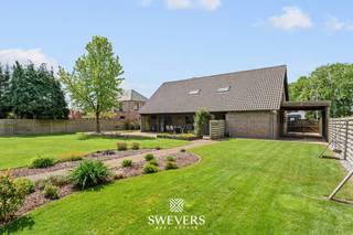 Voor meer info en foto’s, surf naar www.swevers.be – Deze ruime open bebouwing in een rustige straat in Hechtel-Eksel biedt maar liefst 282 m² bewoonbare oppervlakte op een perceel van 14a 15ca. De woning uit 1992 combineert veel leefruimte met een praktische indeling en werd recent opgewaardeerd met onder andere een nieuwe stookolieketel, zonnepanelen, vernieuwde garagepoort en Siemens-toestellen in de keuken. Op het gelijkvloers vindt u een lichtrijke woonkamer van 38 m² met airco, een ruime keuken van 20 m² met toegang tot het terras, een eerste slaapkamer van ca. 16 m², een berging en een apart gastentoilet. De inpandige dubbele garage van 48 m² biedt plaats voor twee wagens en extra stockage. De eerste verdieping telt vier bijkomende slaapkamers, waaronder twee zeer ruime kamers van ca. 32 m² en 28 m². Eén slaapkamer beschikt over airco. De badkamer is uitgerust met een ligbad, dubbele wastafel en toilet, aangevuld met een tweede inloopdouche. Daarnaast is er een ruime kelder van 61 m² en veel zolderruimte voor extra opslag. Buiten geniet u van een groot perceel met een terras van ca. 30 m² en een verzorgde tuin met veel mogelijkheden. Scholen, winkels, openbaar vervoer en ontspanning liggen vlakbij. Ook Nationaal Park Bosland en “Fietsen door de Bomen” bevinden zich in de omgeving. Voor meer informatie, bel 011 255 155. Bron bewoonbare oppervlakte: EPC – verslag.