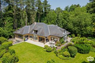 <p><span>Residentieel gelegen villa op een privacyrijk perceel van ca. 2.650 m², tegenover een natuurgebied en nabij het centrum van Heide-Kalmthout, met o.a. een ruime en lichtrijke leefruimte, leefkeuken, vijf royale slaapkamers, drie ingerichte badkamers en een wellnessruimte met binnenzwembad en sauna.  </span></p><p><span>INDELING</span></p><p><span>Gelijkvloers</span></p><p><span>U betreedt de woning via een ruime inkomhal op natuurstenen vloer, voorzien van een gastentoilet met handenwasser en een vestiaire. Deze hal geeft toegang tot de royale en lichtrijke leefruimte op parketvloer, onderverdeeld in een tv-hoek, een zithoek met erker en gashaard en een eetruimte.</span></p><p><span>Aansluitend bevindt zich de volledig uitgeruste leefkeuken met alle hedendaagse toestellen, waaronder een combi-oven, microgolf, inductievuur met ingebouwde dampkap, spoelbak met Quooker-kraan, een grote koelkast, een vriezer en een vaatwasser. De ontbijthoek biedt directe toegang tot het overdekte terras met uitzicht op de prachtig aangelegde tuin.</span></p><p><span>Daarnaast beschikt het gelijkvloers over een masterbedroom op laminaatvloer met aansluitend een dressing en een ingerichte badkamer. Deze is uitgerust met een inloopdouche voorzien van een infrarood Sunshower, een ligbad, dubbele wastafel, toilet en handdoekenradiator.</span></p><p><span>Ten slotte is er nog een dubbele inpandige garage met automatische poort, waar zich eveneens de aansluitingen voor wasmachine en droogkast bevinden.</span></p><p><span> </span></p><p><span>Eerste</span><span> </span><span>verdieping</span></p><p><span>Via de royale trap met vide bereikt u de nachthal, waar zich een apart toilet en een bergkast bevinden. Bovendien heeft u toegang tot een knus balkon. Op deze verdieping bevinden zich vier zeer ruime slaapkamers en een tweede badkamer, ingericht met een douche, ligbad, wastafel, toilet en handdoekenradiator.</span></p><p><span> </span></p><p><span>Zolder</span></p><p><span>Via een vlizotrap heeft u toegang tot de bergzolder.</span></p><p><span> </span></p><p><span>Kelder</span></p><p><span>Middels de centrale trappartij bereikt u de kelder, opgedeeld in drie compartimenten: een bergruimte, een technische ruimte en een ontspanningsruimte. Deze laatste is uitgerust met een zwembad (4 m x 9 m) met jetstream, een traditionele sauna en een badkamer voorzien van een douche, wastafel en toilet. Via een schuifdeur heeft u toegang tot een aangenaam omsloten terras.</span></p><p><span> </span></p><p><span>Tuin</span></p><p><span>De woning is gelegen op een volledig omheind perceel van ca. 2.650 m². De prachtig aangelegde tuin die volledige privacy biedt en veel zoninval geniet, is voorzien van een irrigatiesysteem en meerdere vijverpartijen, die bijdragen aan een rustgevende en groene leefomgeving.</span></p><p><span>Bijzonderheden</span><span><br />-Charmante villa in klassieke/tijdloze stijl <br />-Recent gemoderniseerd o.a. keuken, badkamers, vloeren, …. <br />-Verrassend ruim<br />-Volledige privacy <br />-Fraai aangelegde en goed onderhouden tuin met veel zoninval<br />-Zuid-west georiënteerd<br />-Goed beveiligd<br />-Binnenzwembad en sauna in de kelder met buitenterras<br />-Rustig in het groen gelegen, tegenover natuurgebied en nabij dorpscentrum (scholen, winkels en  openbaar vervoer). <br />-Elektrische keuring is conform.<br />-Geen asbest</span></p><p><span> </span></p>