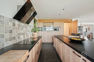 Exclusieve nieuwbouwwoning met 5 slaapkamers, 360 m² woonoppervlakte, toekomstgerichte voorzieningen, en genietend van een prachtig zicht! Bent u op zoek naar een uitzonderlijk ruime en kwalitatieve woning waar comfort, luxe en toekomstgericht wonen centraal staan? Deze in 2023 gebouwde woning biedt maar liefst 360 m² bewoonbare oppervlakte op een perceel van 1.235 m² en werd technisch bijzonder doordacht uitgevoerd.Indeling gelijkvloers: ruime inkomhal, afzonderlijke ruimte ideaal als bureau, apart toilet en een zeer ruime, lichtrijke leefruimte. Aansluitend bevindt zich de luxueuze, volledig geïnstalleerde keuken met hoogwaardige Miele-toestellen, waaronder wijnkoeler, stoomoven, oven, vaatwasser en espressomachine. Verder is er een grote wasruimte met douche en waskoker vanuit de badkamer boven. De inpandige garage biedt plaats aan één wagen, technische installaties en extra stockage.Eerste verdieping: vier slaapkamers, apart toilet en een royale ruimte voorzien voor de inrichting van een wellnessbadkamer, nog volledig af te werken volgens eigen smaak en materiaalkeuze.Zolderverdieping: ingerichte vijfde slaapkamer met verdere afwerkingsmogelijkheden. De voorziene liftschacht loopt door tot deze verdieping.Technisch is de woning bijzonder compleet met vloerverwarming op het gelijkvloers en de eerste verdieping, ventilatiesysteem type D, brede deuropeningen en een liftschacht met bekabeling voor de plaatsing van een inpandige lift.Buiten geniet u van een ruim terras, tuin en meerdere parkeerplaatsen. Bovendien is er een vergunning voor een bijgebouw van 14 m².Een aantal ruimtes dienen nog naar eigen smaak worden afgewerkt, waardoor u zelf de gewenste materialen en inrichting kunt bepalen.Voor wie is dit pand ideaal?♦ Gezinnen die uitzonderlijk veel woonruimte zoeken.♦ Wie comfortabel én toekomstgericht wil wonen.♦ Wie een recente woning verder naar eigen smaak wil afwerken.Een unieke kans voor wie ruimte, kwaliteit en toekomstgericht wooncomfort wil combineren.Bezoek na afspraak met Immo Beguin, jouw vastgoedexpert sinds 2009.Meer info of bezoek via emmy@immobeguin.be