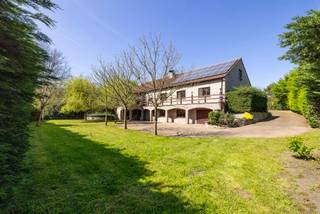 <p>In een groene en uiterst rustige omgeving in Mol, op een <strong>prachtig perceel van 3.010 m²</strong>, bevindt zich dit <strong>zeer ruime landhuis</strong>, opgetrokken met <strong>kwalitatieve materialen</strong>.</p>
<p>Via de ruime inkomhal met gastentoilet kom je in de aangename <strong>leefruimte van meer dan 50 m²,</strong> praktisch ingedeeld in een zithoek met inbouwcassette/open haard en een eethoek. Aansluitend is er een <strong>veranda</strong> die zorgt voor extra lichtinval en een mooi contact met de tuin.</p>
<p>De <strong>keuken</strong> sluit aan op de leefruimte en is uitgerust met onder andere een elektrische kookplaat, vaatwasser en koelkast. Het <strong>granieten werkblad</strong> benadrukt de degelijke afwerking. Op het <strong>gelijkvloers</strong> vind je verder een nachthal met toegang tot <strong>3 ruime slaapkamers</strong> en een extra kamer, ideaal als bureau, <strong>hobbyruimte of 4e slaapkamer</strong>. Daarnaast is er een badkamer met ligbad en toilet, evenals een <strong>dubbele inpandige garage</strong>. De totale bewoonbare oppervlakte van het gelijkvloers bedraagt <strong>ca. 250 m².</strong></p>
<p>Een absolute troef is de <strong>volledig onderkelderde verdieping van ca. 288 m².</strong> Deze is bereikbaar <strong>via 2 vaste trappen</strong>, zowel vanuit het woongedeelte als achteraan via de garage, en beschikt bovendien over <strong>een aparte inkomdeur met inkomhal</strong>. De <strong>garagepoort aan de achterzijde</strong> is bijzonder praktisch om met tuinmateriaal, fietsen of een grasmaaier rechtstreeks de tuin te bereiken.</p>
<p>Deze benedenverdieping is deels ingericht als bruikbare woon-/leefruimte. Zo zijn er momenteel onder meer een <strong>ruime wasplaats</strong>, <strong>2 extra kamers, een ruime hobbykamer en een 2e badkamer met sauna, inloopdouche, wastafel en toilet</strong>. Daarnaast zijn er nog meerdere voorraadkelders, ideaal voor stockage.</p>
<p>Ook de <strong>zolderverdieping</strong>, bereikbaar <strong>via een vaste trap, biedt met ca. 194 m² </strong>nog heel wat <strong>uitbreidingsmogelijkheden</strong> voor extra kamers, een speelruimte, hobbyruimte of thuiskantoor, afhankelijk van de technische haalbaarheid en gewenste invulling.</p>
<p>Rondom de woning ligt een enorm, groen en zeer goed onderhouden tuinperceel waar je in alle rust en privacy kan genieten. Extra troef is de ruime <strong>straatbreedte van ca. 38 meter</strong>, wat zorgt voor een mooie, open inplanting. Er is bovendien ruim <strong>voldoende parkeergelegenheid</strong> aan en rond de woning.</p>
<p>De woning beschikt over tal van hedendaagse comfort- en energietroeven, waaronder <strong>vloerverwarming, zonnepanelen, airco, sproei-installatie in de tuin, sauna, een gunstige EPC-score met label B en een asbestveilig attest.</strong></p>
<p><strong><em><u>Kortom</u>: dit uitzonderlijk ruime landhuis biedt mogelijkheden voor maar liefst <u>3 woonentiteiten</u> en is daardoor ideaal voor <u>kangoeroewonen</u>, een groot gezin of <u>zelfstandigen</u> die bijvoorbeeld een kine- of dokterspraktijk aan huis wensen. Een uniek eigendom; aan de snelle beslissers! </em></strong></p>