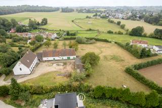 Aan de zuidflank van Wemmel, op de grens tussen stad en stilte, ligt een plek die nog ademt wat ooit was: het Ronkelhof. Verspreid over ruim één hectare glooiend landschap, vormt deze historische hoeve een zeldzaam relict van het landelijke leven rond Brussel.<br /><br />Het Ronkelhof gaat terug tot de 18de eeuw en was ooit deel van een middeleeuwse vierkantshoeve. Vandaag staat het als enige authentiek bewaarde pachthof in Wemmel, met zijn witgekalkte bakstenen gebouwen, gepikte plint en karakteristieke zadeldaken. De site is gelegen op een heuvel en bereikbaar via een holle weg, een schilderachtig toegangspad dat haast tijdloos aanvoelt.<br /><br />De gebouwen, vandaag niet meer bewoonbaar, wachten op een renovatie die hun historische waarde eer aandoet. Hier ligt een uitzonderlijke kans voor wie erfgoed een toekomst wil geven, in ruil voor rust, ruimte en een unieke locatie vlak bij de hoofdstad. De boomgaard achteraan herinnert aan het landleven van vroeger en vormt een stille belofte van eenvoud en natuur.