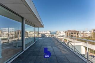 Wakker worden met zicht op de Wellington Golf, met de zee aan de horizon. Dat is wat dit uitzonderlijke duplex-penthouse in Oostende zo bijzonder maakt.<br /><br />Gelegen op de zesde en zevende verdieping woon je hier op een toplocatie, vlak bij het strand en op wandelafstand van winkels. Vanuit het appartement geniet je van een open zicht over het groen van de golf en de zee, terwijl de verschillende terrassen ervoor zorgen dat je zowel binnen als buiten volop van die ligging kan genieten.<br /><br />Met 156 m² bewoonbare oppervlakte is er hier bovendien geen gebrek aan ruimte. De echte troef is echter de indrukwekkende 136 m² aan terrassen. Rondom het penthouse vind je verschillende buitenruimtes, waardoor je op elk moment van de dag wel een plek vindt om van de zon, het uitzicht of een rustige ochtend te genieten.<br /><br />Op de zesde verdieping bevinden zich twee ruime slaapkamers. Beide slaapkamers hebben rechtstreeks toegang tot een terras met open zicht op de Wellington Golf. Verder vind je hier een stijlvolle badkamer met ruime inloopdouche, ligbad en dubbel lavabomeubel, een apart gastentoilet en een praktische berging met aansluiting voor de wasmachine.<br /><br />De zevende verdieping vormt het hart van de woning. De ruime leefruimte is bijzonder lichtrijk dankzij de grote raampartijen en beschikt over een prachtige visgraatparket en een gezellige gashaard. Het open zicht zorgt hier voor een bijzonder gevoel van ruimte en maakt van de leefruimte een plek waar je vanzelf wat langer blijft zitten.<br /><br />De open keuken sluit mooi aan bij de leefruimte en is volledig uitgerust met hoogwaardige Siemens-toestellen. Of je nu rustig met z'n tweeën ontbijt of vrienden over de vloer krijgt, alles staat hier in het teken van comfortabel wonen en genieten.<br /><br />Vanuit de leefruimte stap je rechtstreeks het grote zonneterras op. Met zijn royale oppervlakte is dit de ideale plek voor een lange zomeravond, een aperitief met zicht op de golf of gewoon om even helemaal tot rust te komen. De grens tussen binnen en buiten vervaagt hier volledig.<br /><br />De combinatie van de royale woonoppervlakte, de uitzonderlijke hoeveelheid terrasruimte, de verzorgde afwerking en vooral het open zicht op de golf en de zee maakt dit een penthouse met een heel eigen karakter. Een plek waar je niet alleen aan de kust woont, maar er elke dag volop van geniet.<br /><br />Er is bovendien de mogelijkheid om een garagebox in dezelfde residentie aan te kopen.<br /><br />Mogelijkheid om aan minder dan 2% registratierechten aan te kopen.