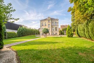 A rare property for its volumes, its character and its possibilities.
In Lembeek, part of Halle, this remarkable late-19th-century mansion house offers approx. 571 m² of living space on a plot of 19a 54ca (1,954 m²).
Fully renovated in 2014, the house has retained many of the features that give it its charm: marble mosaic, blue stone, oak parquet, solid plank floors, high ceilings and marble fireplaces.
With 8 bedrooms, 2 bathrooms, a shower room, 2 kitchens and 4 levels, the property offers a wealth of options: a large family home, multigenerational living, space for a home practice, or a house in which a self-contained unit can be created as needed.
GROUND FLOOR
Spacious entrance hall with original mosaic floor and period staircase. To the right, the dining room with wood stove, leading into the fitted kitchen: SMEG range cooker, induction hob, two ovens and dishwasher. To the left, a very large two-part living room, filled with light from wide windows, with two wood stoves in marble fireplaces.
FIRST AND SECOND FLOORS
Four large rooms and a bathroom on each floor, free to arrange as you wish: bedrooms, study, dressing room or playroom. Throughout: high ceilings, preserved marble fireplaces, wooden floors and green views. Air conditioning on this level.
LOWER LEVEL, OPENING ONTO THE GARDEN
With its direct access at the rear, this level works as a separate living unit: a large fitted kitchen with wood stove, an additional room, a shower room with separate WC, a laundry room, a plant room and several dry storage cellars.
GARDEN AND PARKING
Almost 20 ares, fully landscaped: a wide cobbled terrace along the house, a large lawn, mature trees, a garden pavilion and a fixed play area. Cobbled driveway at the front, two entrance gates, a property that can be fully closed off and parking for several cars.
TECHNICAL
Complete renovation in 2014 and windows replaced in 2018. Gas central heating with condensing boiler throughout the house; the wood stoves are an extra for atmosphere and additional warmth. Domestic hot water from a solar water heater (4.8 m² of collectors).
LOCATION
Lembeek (Halle): bus stop and shops within walking distance, quick access to the town centre, the station, Brussels and the E19/R0. Schools and childcare nearby.
This property truly reveals itself on a visit. Call 0486 13 12 70 or email oliva.claes@claeswillems.be.