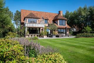 Prachtige villa met weids polderzicht en uitgestrekte tuin met zonneterrassen. <br />Op een boogscheut van Knokke, nabij Duinenwater.<br />Indeling gelijkvloers: Inkomhal met vestiaire en apart toilet. De open lichtrijke leefruimte beschikt over een open haard, ruime eetkamer, de ruime volledig geïnstalleerde keuken is voorzien van alle comfort en geeft uit op het terras en de tuin. Daarnaast is er ook een grote bijkeuken en een praktische wasplaats/berging. <br />Op de eerste verdieping: De masterbedroom met ensuite badkamer (ligbad, inloopdouche, dubbele lavabo en toilet) geeft uit op het ruim terras met open zichten. De tweede slaapkamer is voorzien van ingemaakte kasten en een badkamer met ligbad, inloopdouche, dubbele lavabo en toilet. Aanpalend is er een terras met uitzicht op de velden. De derde slaapkamer is uitgerust met een douchekamer (inloopdouche, lavabo en toilet).<br />Grote zolder waar 2 extra slaapkamers en een badkamer kunnen ingericht worden.<br />Garage voor fietsen. Meerdere buiten staanplaatsen.<br />EPC: 129 kWh/m²