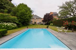 <p>In het centrum van Berendrecht vindt u deze karaktervolle, vrijstaande villa met een rijke afwerking en een verzorgde tuin met bijgebouw en zwembad. Een woning die ruimte, stijl en comfort moeiteloos combineert.</p>
<p>Bij het binnentreden valt meteen de inkomhal op, een natuurstenen vloer en een sierlijke trap met een leuning in messing zetten de toon voor de rest van de woning.</p>
<p>Op het gelijkvloers niveau bevindt zich een elegante eetkamer geschikt voor grote tafelgezelschappen en een ruim salon op parket met open haard. Beide ruimtes geven via open slaande deuren uit op de tuin. De volledig uitgeruste keuken met kookeiland, inbouwtoestellen van topmerken en aansluitend ontbijthoek vormt het kloppend hart van de woning. Via de keuken heeft u tevens toegang tot het aangename, Zuid-georiënteerde terras.</p>
<p>Een bijkomende bureauruimte biedt de ideale plek om thuis te werken of als praktijkruimte. Het tweede formele salon kan tevens omgevormd worden als bureau zodoende de woning ideaal geschikt is om een vrij beroep te combineren.</p>
<p>De villa telt maar liefst 7 slaapkamers, verdeeld over de verdiepingen, waaronder een ruime master bedroom met eigen badkamer en dressing. Bijkomende bergruimte en uitbreidingsmogelijkheden vindt u op de tweede verdieping, terwijl de kelder de ideale plek vormt om wijn te bewaren.</p>
<p>Een weelderige, aangelegde tuin wordt omsloten door hoge, volwassen hagen en bomen, die zorgen voor een uitzonderlijke mate van privacy zonder in te boeten aan lichtinval. Her en der zorgen bloeiende hortensia's, weelderige rozenstruiken en sierlijke coniferen voor kleur en karakter doorheen de seizoenen.</p>
<p>Aan de achterzijde van de tuin bevindt zich het karaktervolle bijgebouw in baksteen, met trapgevel en windhaan op de schoorsteen – een charmante blikvanger die meteen de authentieke uitstraling van het geheel versterkt. Het bijgebouw grenst aan een tweede, intiemere zithoek bij het zwembad en biedt extra mogelijkheden als poolhouse, gastenverblijf of atelier.</p>
<p>Het wooncomfort wordt verhoogd met een dubbele inpandige garage. Kortom een villa met karakter, ruimte en comfort.</p>