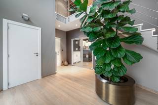 Strategisch gelegen en volledig gerenoveerde high-end villa met een bewoonbare oppervlakte van ca. 400 m², aangevuld met een aparte garage/magazijn van 75 m². Dankzij de vlotte verbinding met de E19 geniet u van een uitstekende bereikbaarheid richting Antwerpen en Brussel.<br /><br />Deze eigendom is bovendien uitermate geschikt voor het combineren van wonen en werken, ideaal voor vrije beroepen of zelfstandige activiteiten.<br /><br />Indeling & comfort:<br /><br />U wordt verwelkomd in een ruime en lichtrijke inkomhal met elegante trap. Van hieruit betreedt u de royale leefruimte met open, hyper uitgeruste keuken en groot kookeiland. De grote raampartijen zorgen voor een overvloed aan natuurlijk licht en een prachtig zicht op de verzorgde tuin.<br /><br />Aansluitend bevindt zich een praktische berging met ingemaakte kasten, die toegang biedt tot de inpandige garage met plaats voor 2 à 3 wagens.<br /><br />Naast de woning is er bovendien een afzonderlijke garage/magazijn van ca. 75 m², geschikt voor meerdere voertuigen (tot 4 wagens) of professionele doeleinden.<br /><br />Verdiepingen:<br /><br />Op de eerste verdieping vindt u:<br />een zeer ruim bureau met apart archief<br />een grote wasplaats<br />3 volwaardige slaapkamers<br />een badkamer met inloopdouche en hoekbad<br /><br />De tweede verdieping biedt:<br />een ingemaakte dressing<br />een ruime master bedroom<br />een luxueuze badkamer met inloopdouche en bubbelbad voor 2 personen<br />een zolderruimte met extra opbergruimte en technieken<br /><br />Technische troeven:<br /><br />Deze woning is uitgerust met alle moderne comfort:<br />uitgebreid domoticasysteem<br />alarminstallatie en camerabewaking<br />60 zonnepanelen<br />airconditioning<br />zonneweringen