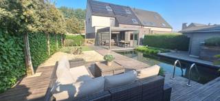 Instapklare energiezuinge gezinswoning (EPCA) met uitzonderlijke tuinbeleving Deze hoogwaardige halfopen bebouwing combineert energiezuinig wonen, ruimte en luxe met een uitzonderlijk buitenleven. Dankzij de verwarmde zwemvijver en de stijlvolle terrasoverkapping met lamellendak geniet je hier het hele jaar door van een vakantiegevoel in eigen tuin.Binnen word je verwelkomd in een lichtrijke leefruimte met natuurstenen vloer, ingemaakte kasten en een aangename verbinding met de tuin. De semi-open keuken is volledig uitgerust en praktisch ingericht, met aansluitend een berging met wasruimte, extra douchekamer en toilet.De hoogwaardige maatwerktrap lijd je naar de ruime bovenverdieping waarop zich 3 volwaardige slaapkamers bevinden, waarvan 1 met ingemaakte kasten en bureau en 1 met ruime dressing die rechtstreeks toegang biedt tot een ruime badkamer met ligbad, inloopdouche, toilet en dubbele lavabo.De buitenruimte is een absolute troef: een onderhoudsvriendelijke tuin met tuinhuis, verwarmde zwemvijver en een Brustor terrasoverkapping als volwaardige extra leefruimte dankzij de glazen schuifwanden, zonnescreen en een infrarood verwarmingselement.Technisch en energetisch blinkt deze woning uit met o.a. EPC A, zonnepanelen, laadpaal, regenwaterrecuperatie, elektrische rolluiken, vliegenramen en een recent vernieuwde Bosch condensatieketel.Er is een inpandige garage met 2 extra parkeerplaatsen op de oprit.De groene omgeving met landelijk karakter en de vele wandel- en fietsmogelijkheden maken het plaatje compleet.Ook de vlotte verbinding met de E34 en de haven van Antwerpen en Gent zijn een troef.Een instapklare woning voor wie comfort, rust en kwaliteit zoekt zonder verplichte renovaties.Interesse? contact@eberhardvastgoed.be of 03 / 779 69 29.