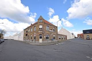 Uniek hoekpand met handelsruimte en woonst te Beerst (Diksmuide) op 470 m². Het eigendom is ingedeeld met handelsruimte/ kantoor/ winkel (momenteel horeca = 175 m²) + feestzaal (75 m²) , garage voor 3 wagens, toiletten, bergruimte, diepvries en frigocel, droge kelder en zonnig terras. Op het verdiep is een mooi 3 slaapkamer appartement met recente ingerichte keuken, lichtrijke leefruimte, badkamer. Grote zolder via vaste trap. Vrij van brouwer. UC: 1047285 EPC: 249 kwh/m². (Ref. NI21828)