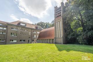 Op zoek naar een karaktervol erfgoedappartement te koop in Halle, vlak bij Brussel? Dit ruime gelijkvloerse appartement van ca. 111 m² beschikt over een inkomhal, een ruime living, een afzonderlijke keuken, een badkamer, een wasplaats, een grote slaapkamer en een kleinere kamer die geschikt is als tweede slaapkamer, bureau, dressing of hobbyruimte.
Het appartement heeft het exclusieve genot van zowel het terras als de aansluitende tuin, die nog moet worden omheind. Zo combineert u het comfort van een appartement met een private buitenruimte in een uitzonderlijk groene omgeving.
De eigendom maakt deel uit van het voormalige sanatorium van Henry Lacoste uit 1927, gelegen op een beschermd privédomein van ongeveer 7 hectare. Via de Ring en het station van Buizingen bereikt u Brussel in ongeveer 15 à 20 minuten.
Voor het gebouw wordt een professioneel renovatieplan uitgewerkt met het oog op een gefaseerde totaalrenovatie, met respect voor het historische en architecturale karakter.
Het appartement wordt aangeboden met een vanafprijs. Een ondergrondse garagebox kan afzonderlijk worden aangekocht vanaf € 25.000.